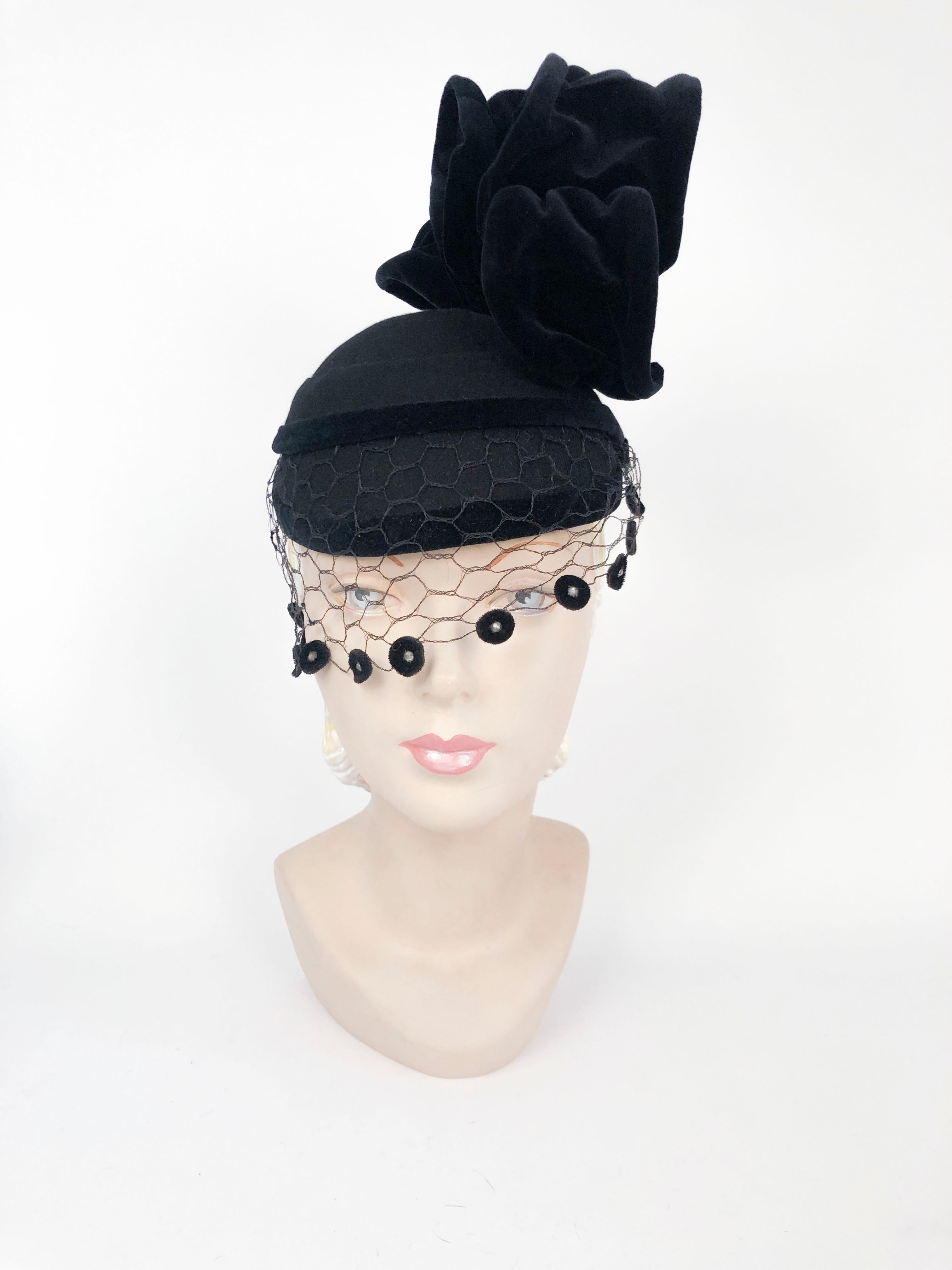 1930s Perch hat made of a black beaver fur felt trimmed in velvet and decorated with a structured fan accent atop the head and a partial veil decorated with velvet discs and set rhinestones. 