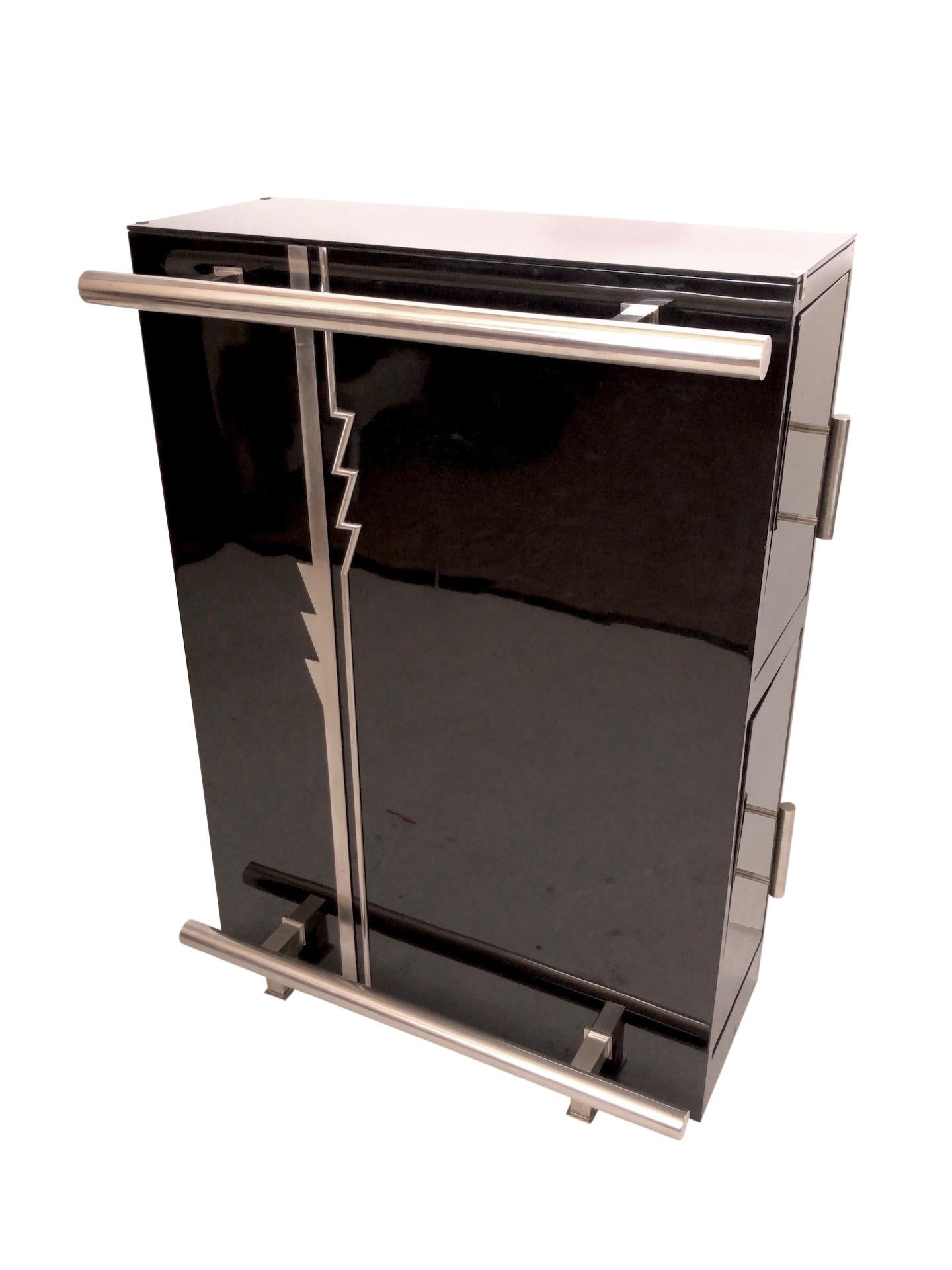 Metal Art Deco pattern in front of this dry bar furniture
Black piano lacquer 
Nickeled metal 
The black glass top is the perfect protection against alcohol and liquids. 
on both sides with drawers 

Place it directly on the wall and one or