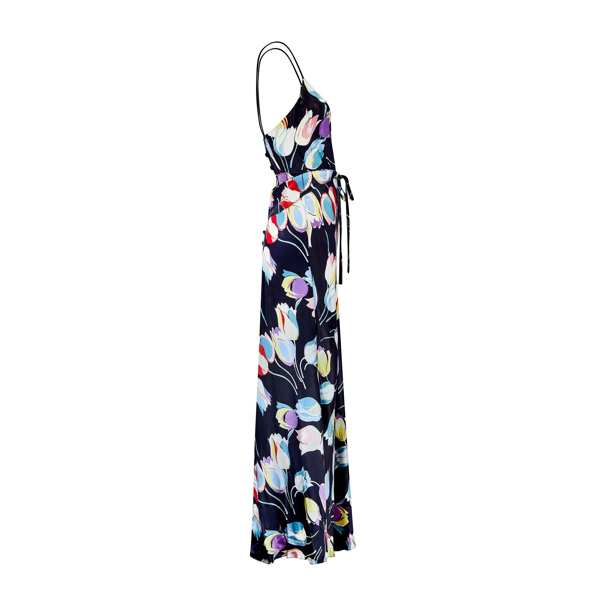 Designed in the 1930s, this beautiful, vibrant liquid satin evening dress is a spectacular example from this era. The fabric makes it stand out among other pieces from this time; inky black satin is scattered with tulips rendered in painterly