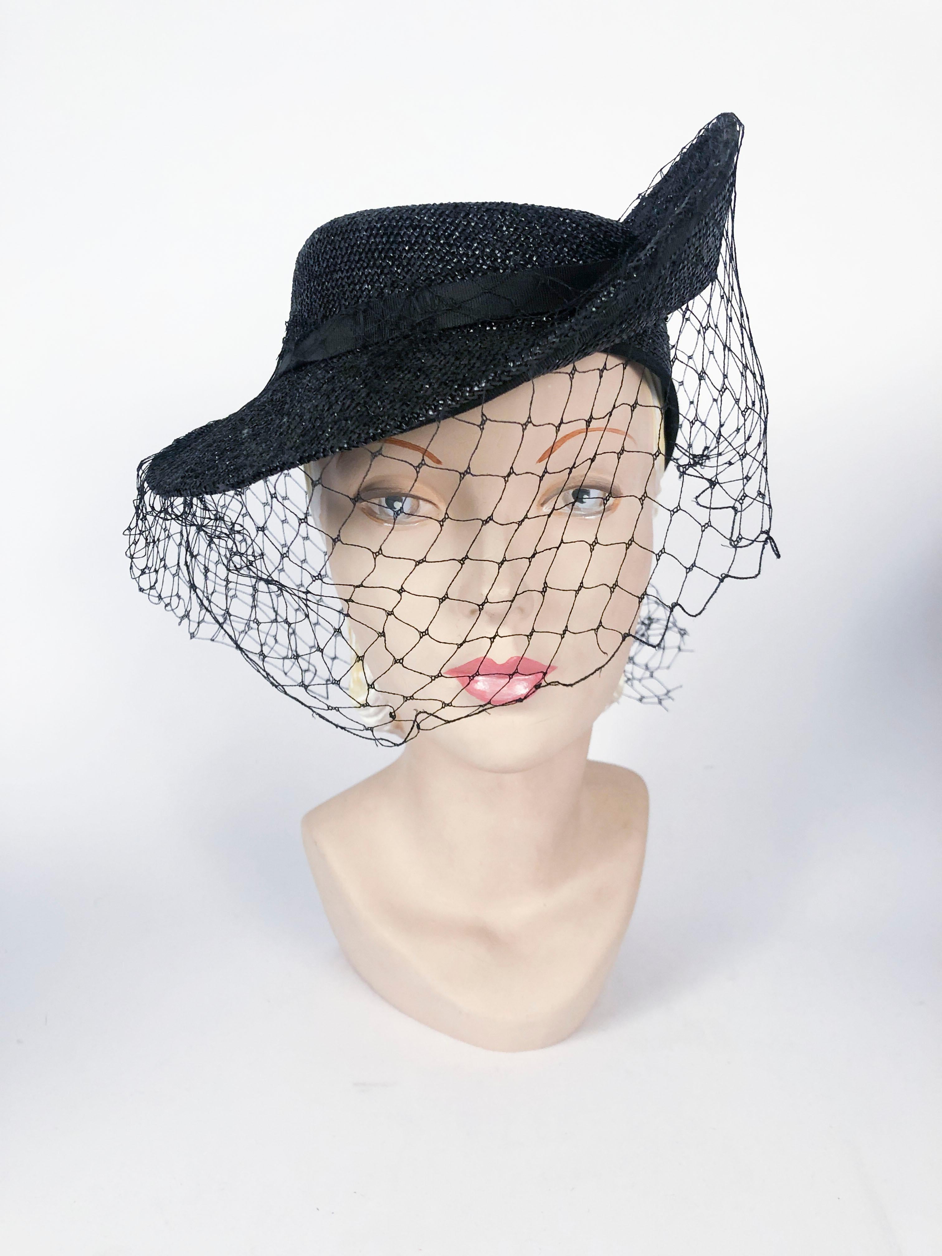 1930s black woven straw hat with asymmetrical brim, gros-grain band, and a full matching net. There is an elastic hair band that further holds the hat to the head.