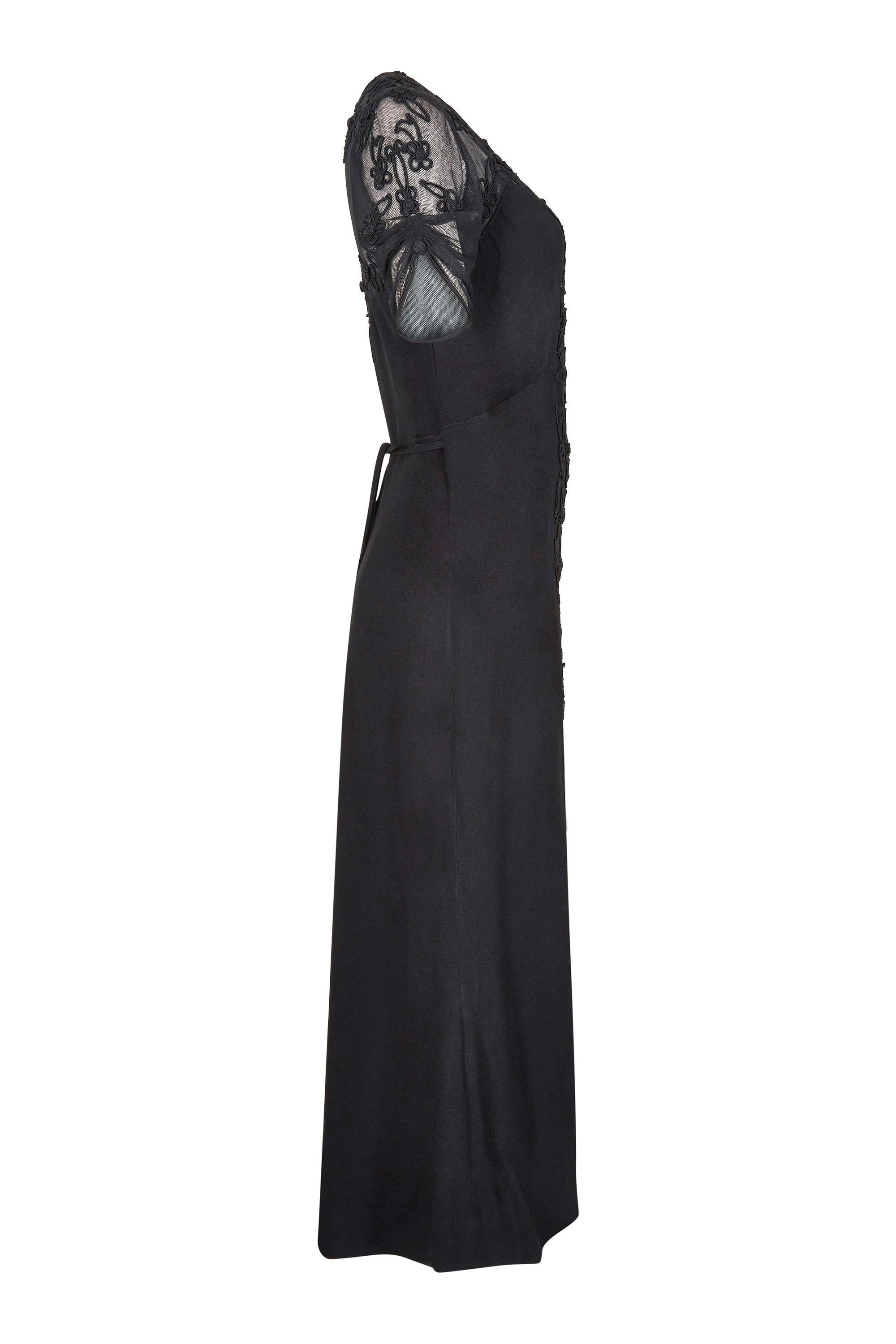 This incredible 1930s black silk crepe evening dress with soft net bodice is in fantastic vintage condition with some beautiful design features. The dress has a plunging scoop neckline and sheer net fabric on the shoulders and upper back. The soft