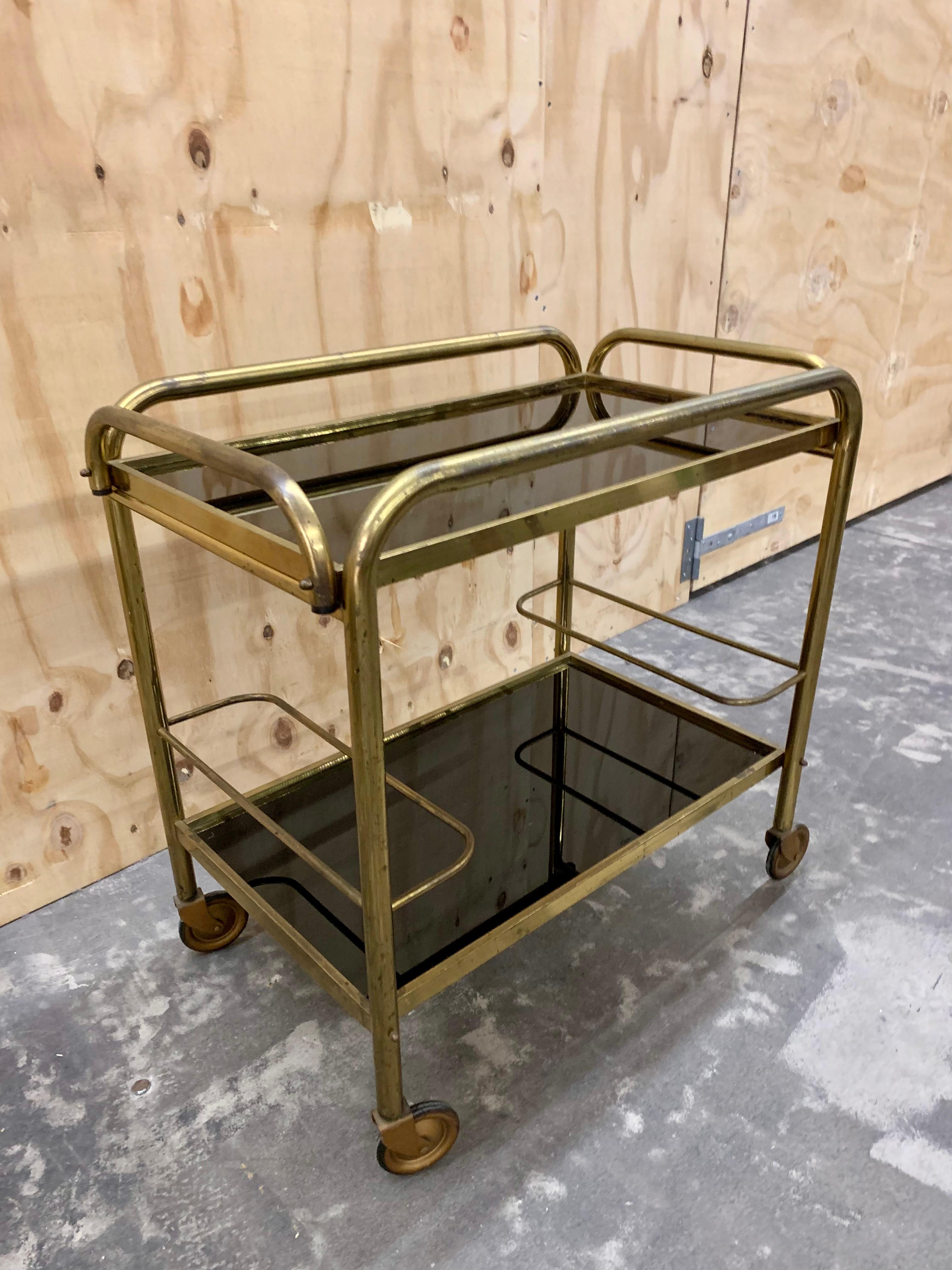 Vintage French brass bar cart - drinks trolley with table tops in black glass and holders for bottles on the lower shelf.