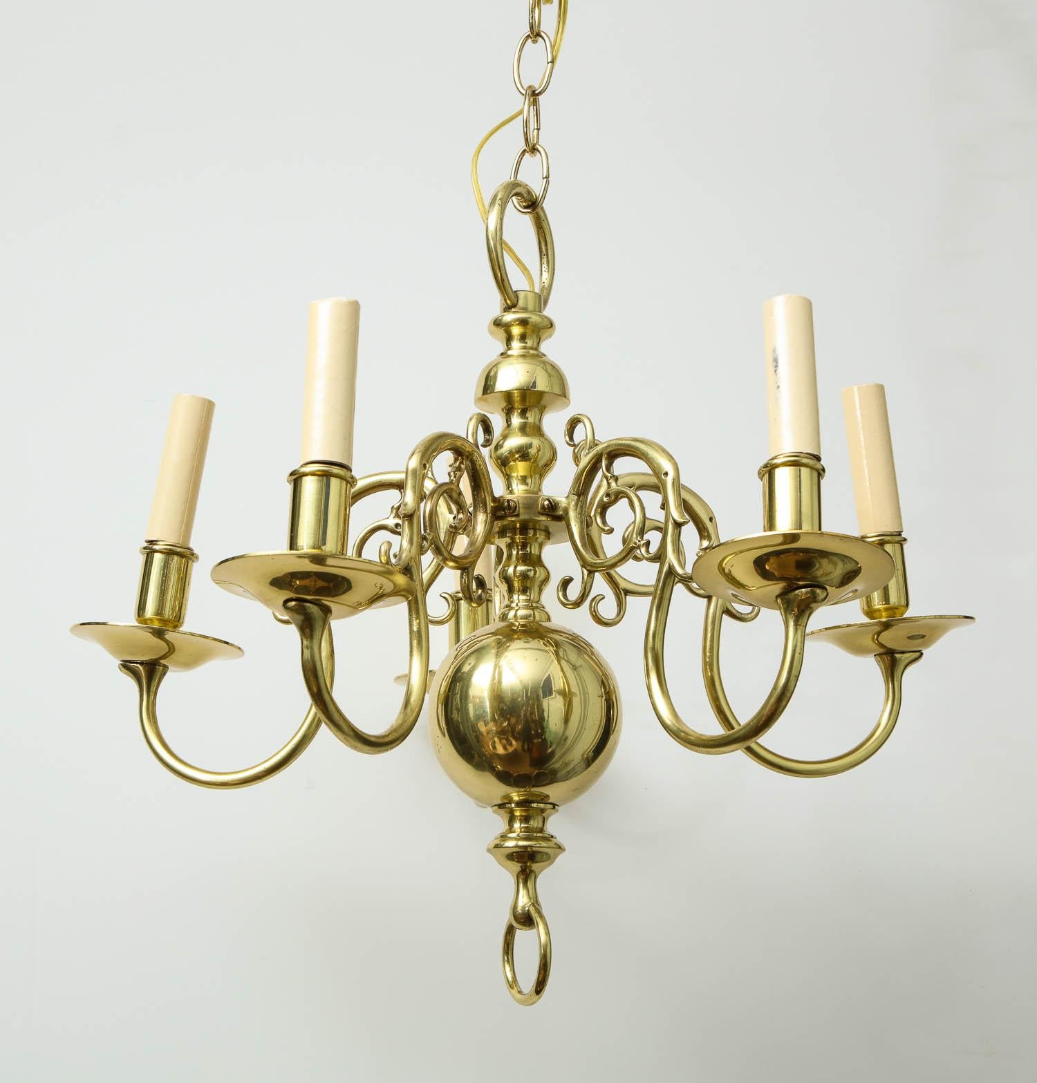 Good 20th century brass five-light chandelier with scrolled arms, the turned center shaft with large ball pediment with suspended ring. Recently polished and rewired.

Measures: 16