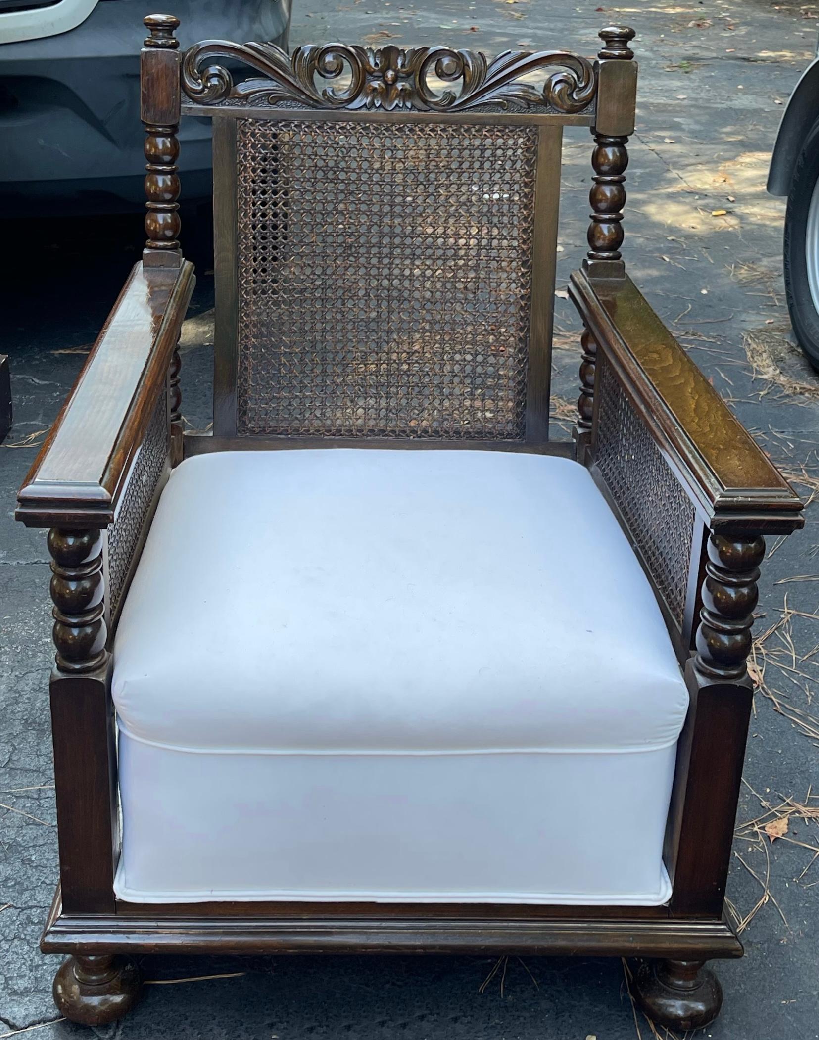 This is a pair of English British Colonial style carved oak and cane back club chairs. The white cotton upholstery is vintage but in good condition. The chairs include a loose back cushion and pillow. See the coordinating sofa. 

One can panel