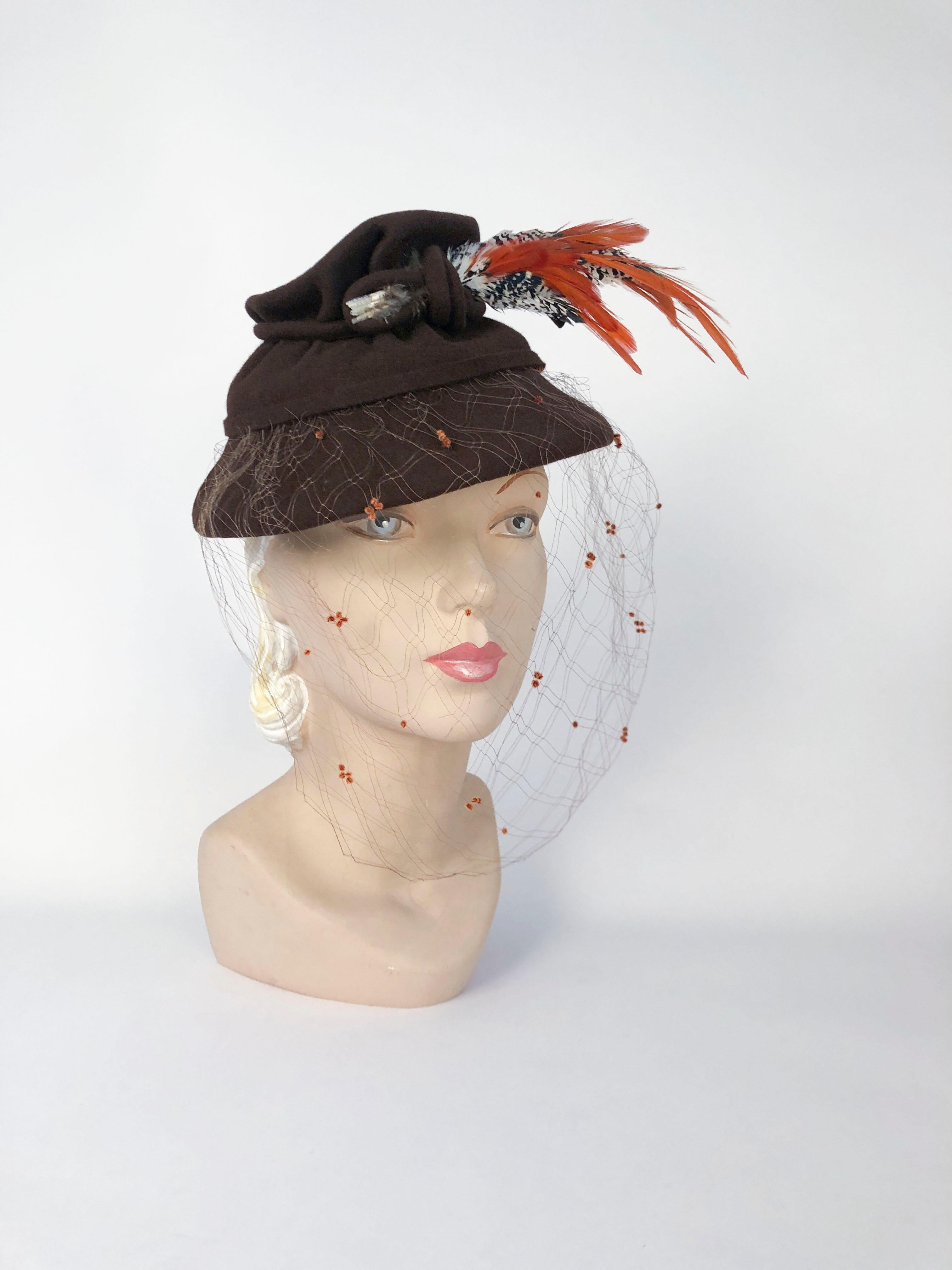 1930's tri-layered brown structured hat decorated with cord-work, multi-colored bird feathers, and a full-face veil that has velvet flecks