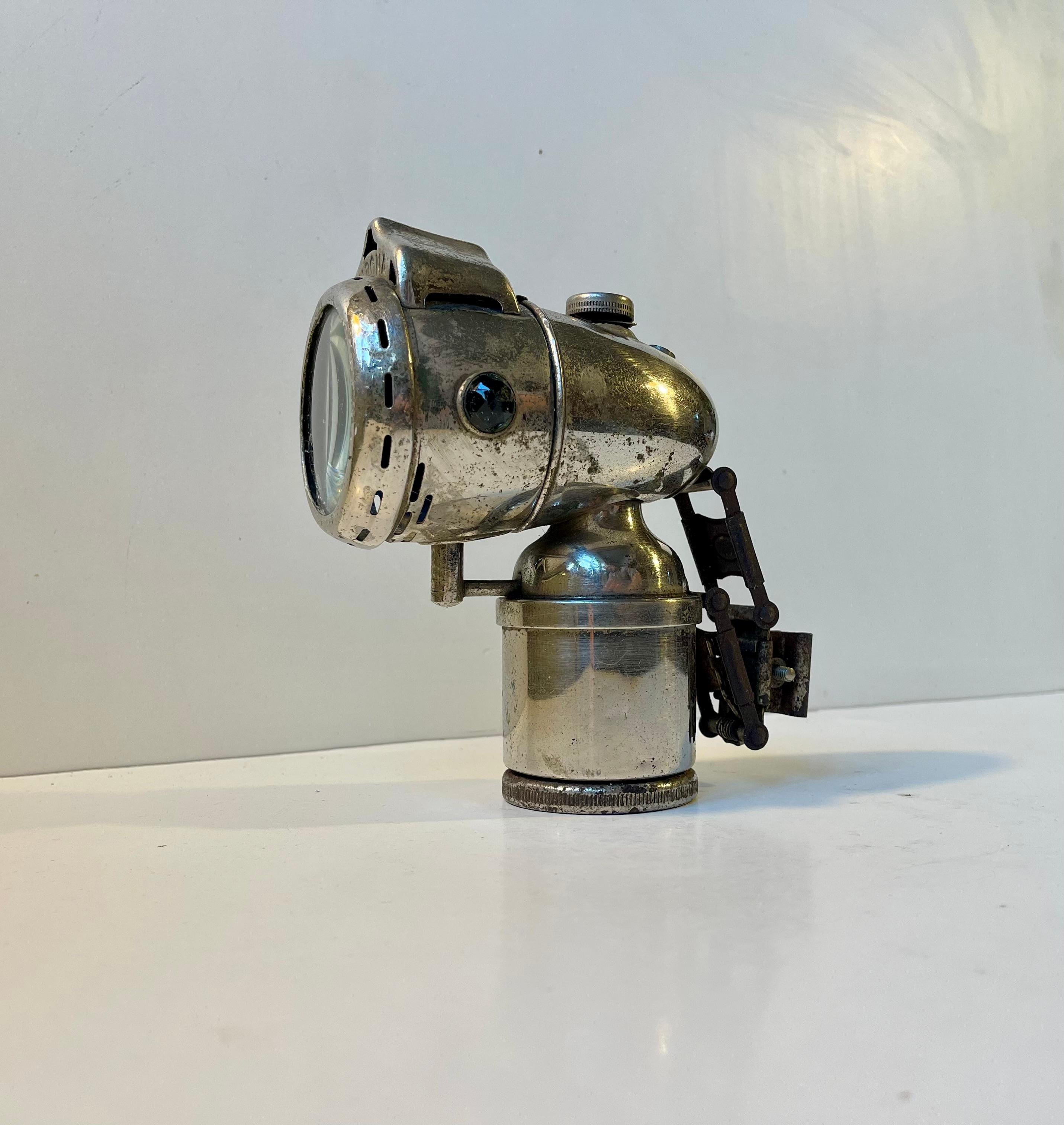 Lampe de bicyclette à gaz carbure des années 1930. Fabriqué par Nirona en Allemagne dans les années 1930. Cette lampe semble intacte mais n'a pas été testée. La vitre frontale est munie d'un nik. 

Dimensions : H : 17 cm, Dept : 16/13 cm, Width :
