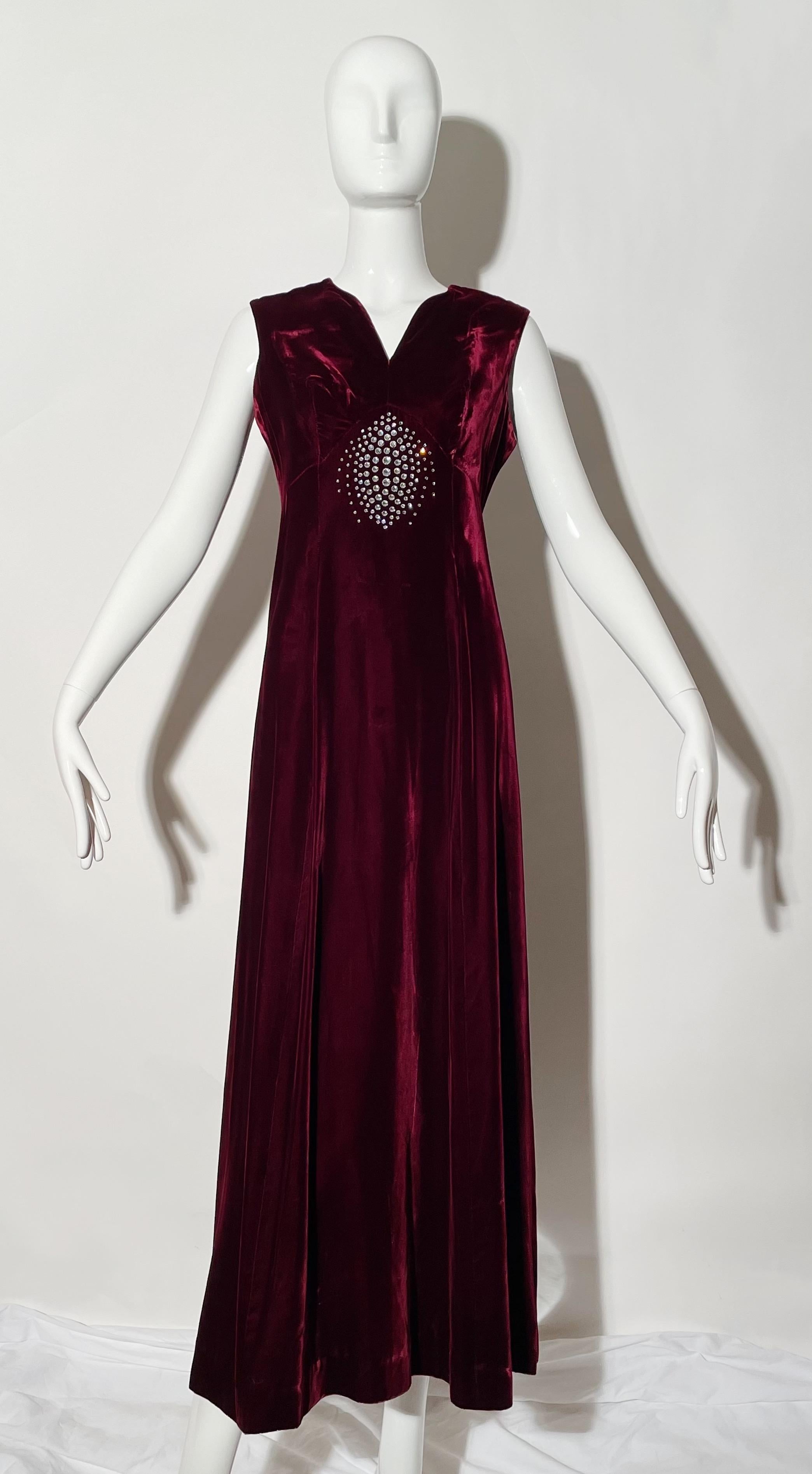 Burgundy velvet gown. Rhinestone detail. Sleeveless. Rear zipper. Lined. 
*Condition: excellent vintage condition. No visible flaws.

Measurements Taken Laying Flat (inches)—
Shoulder to Shoulder: 14 in.
Bust: 12 in.
Waist: 28 in.
Hip: 32