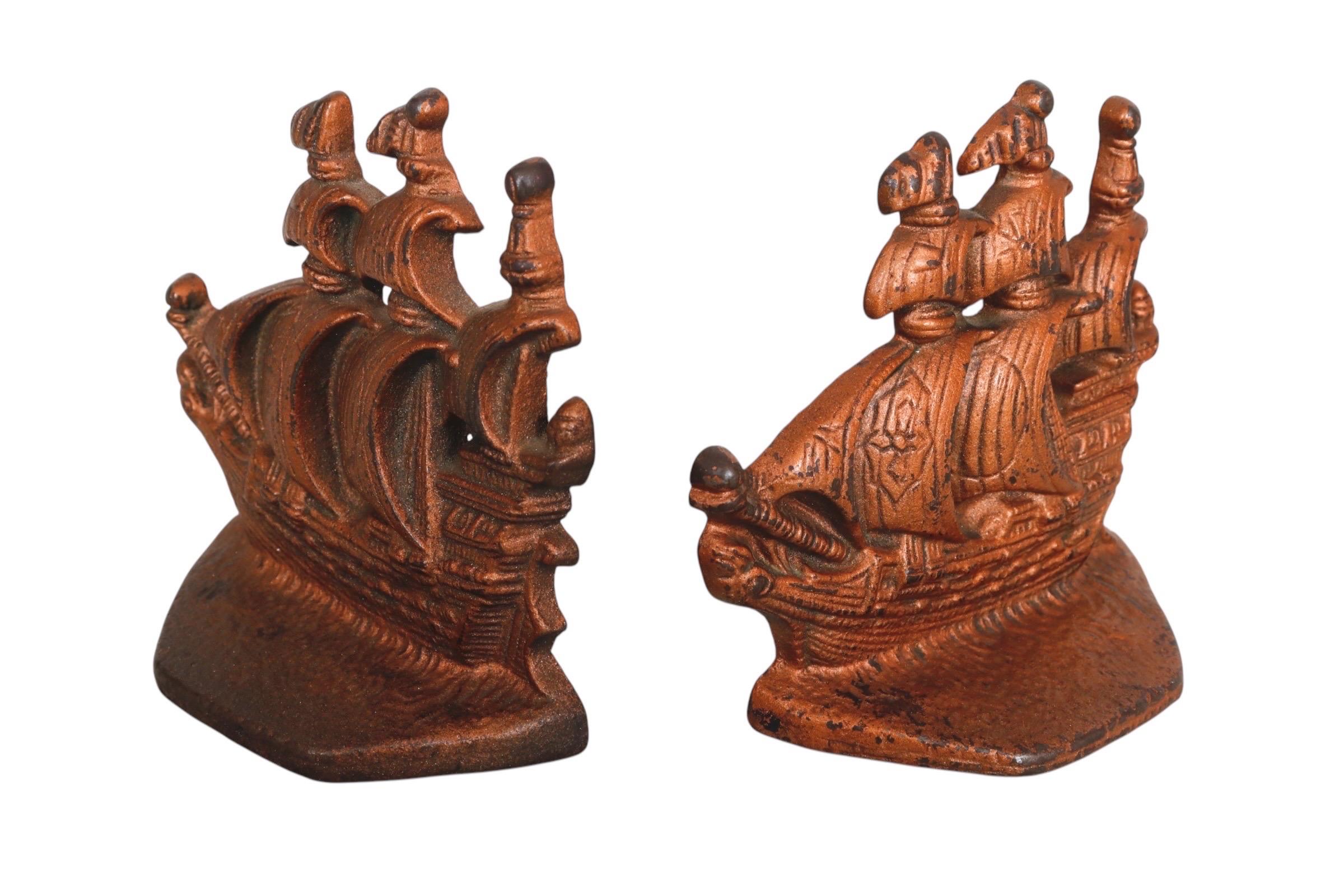 A pair of nautical 1930’s cast iron bookends in a copper finish. Shaped like carrack ships with full sails, decorated with a cross. Dimensions per bookend.