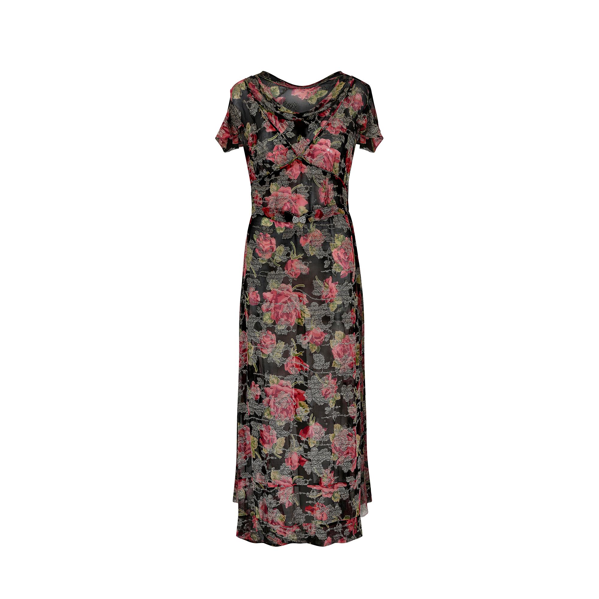 Cette robe en mousseline de soie des années 1930 est ornée d'un magnifique motif de roses et de délicats détails en lames de couleur champagne. Elle est coupée dans le biais classique, avec un col bénitier légèrement lesté. Il s'agit d'une