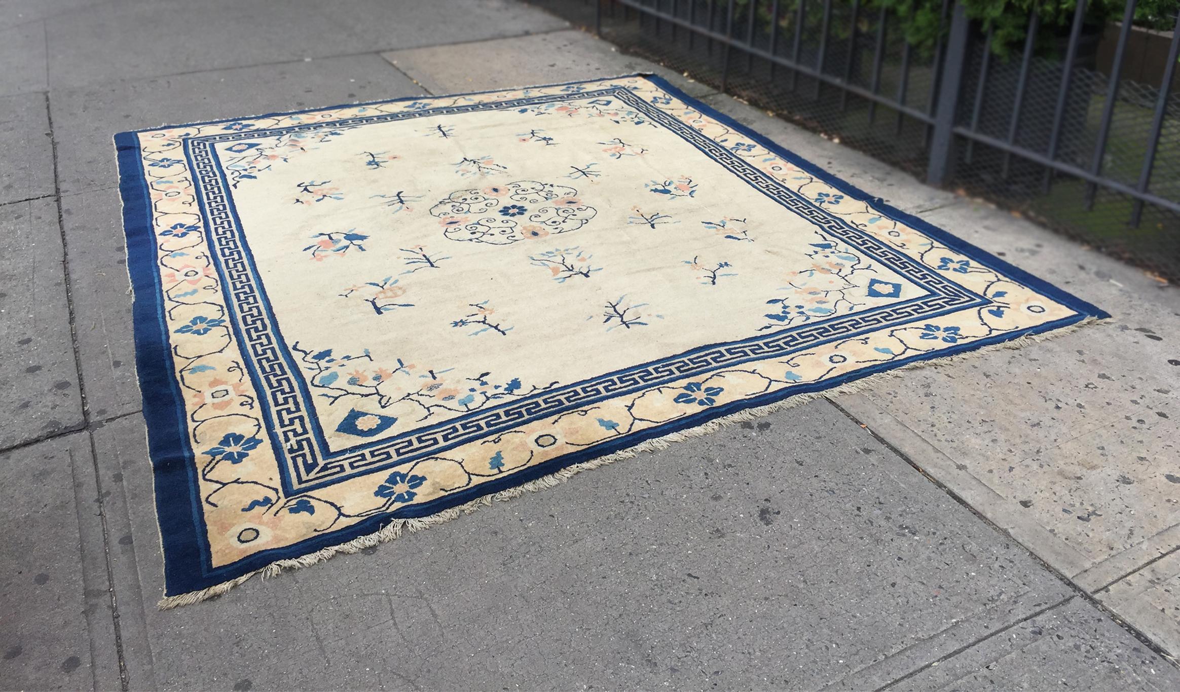 This Chinese Art Deco rug was handcrafted in the 1930s. The elegant design is composed of a central medallion with blue flowering curlicues and peach-hued blossoms set in a light tan field. Around the medallion are two rings of flowering branches