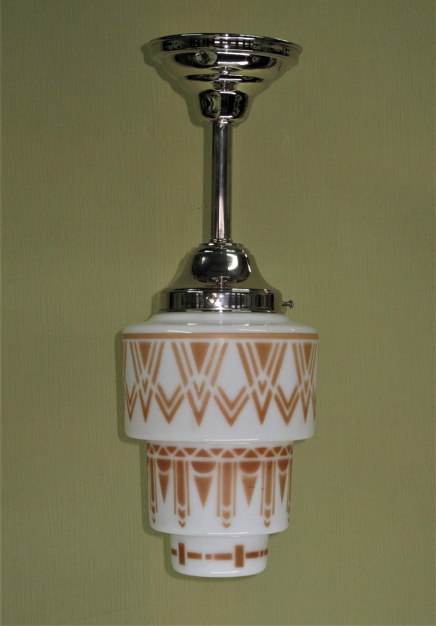 Colorful and playful vintage Art Deco globe shown on a new Nickel plated fitter. The Deco design, which has been stenciled and fired onto the glass is a color not quite red and not quite brown, Cinnamon. Although the design has a very Deco flavor it