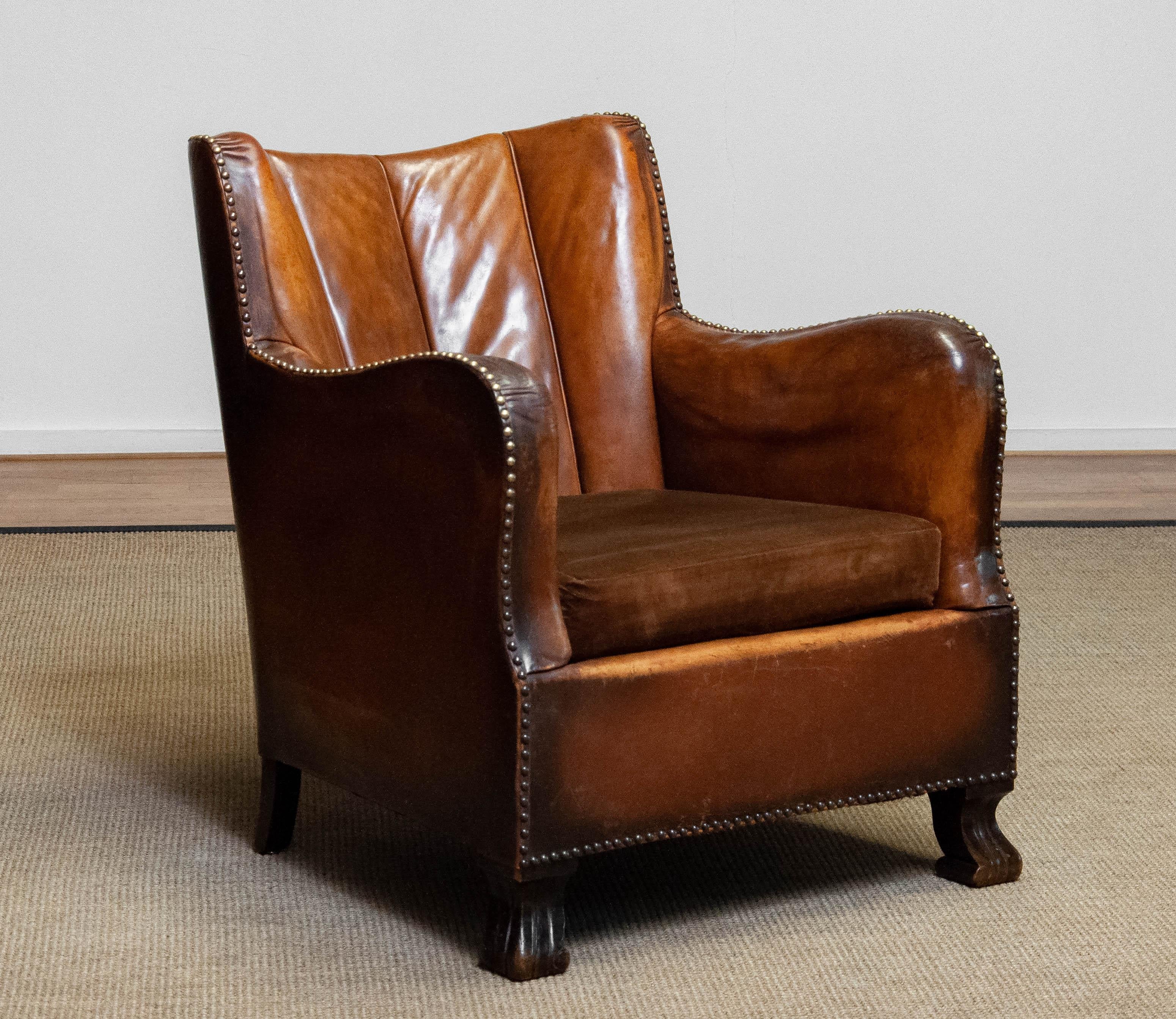 Very characteristic tan brown leather sugar / club chair from around the 1940s from Denmark and attributed to Oskar Hansen. This club chair in her complete and original condition. The absolute fantastic patina on the leather combined with the brass
