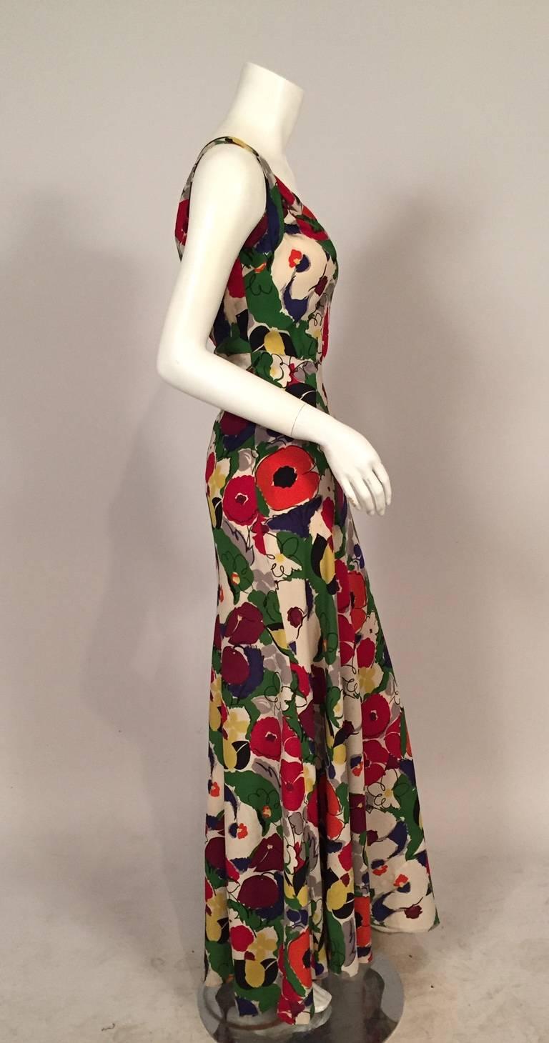 A striking and colorful floral print in bright cheerful primary colors makes a very eye catching evening dress. The neckline is gathered at the center front and plunges to a deep V in back. The dress has a slightly raised waistline and a flowing