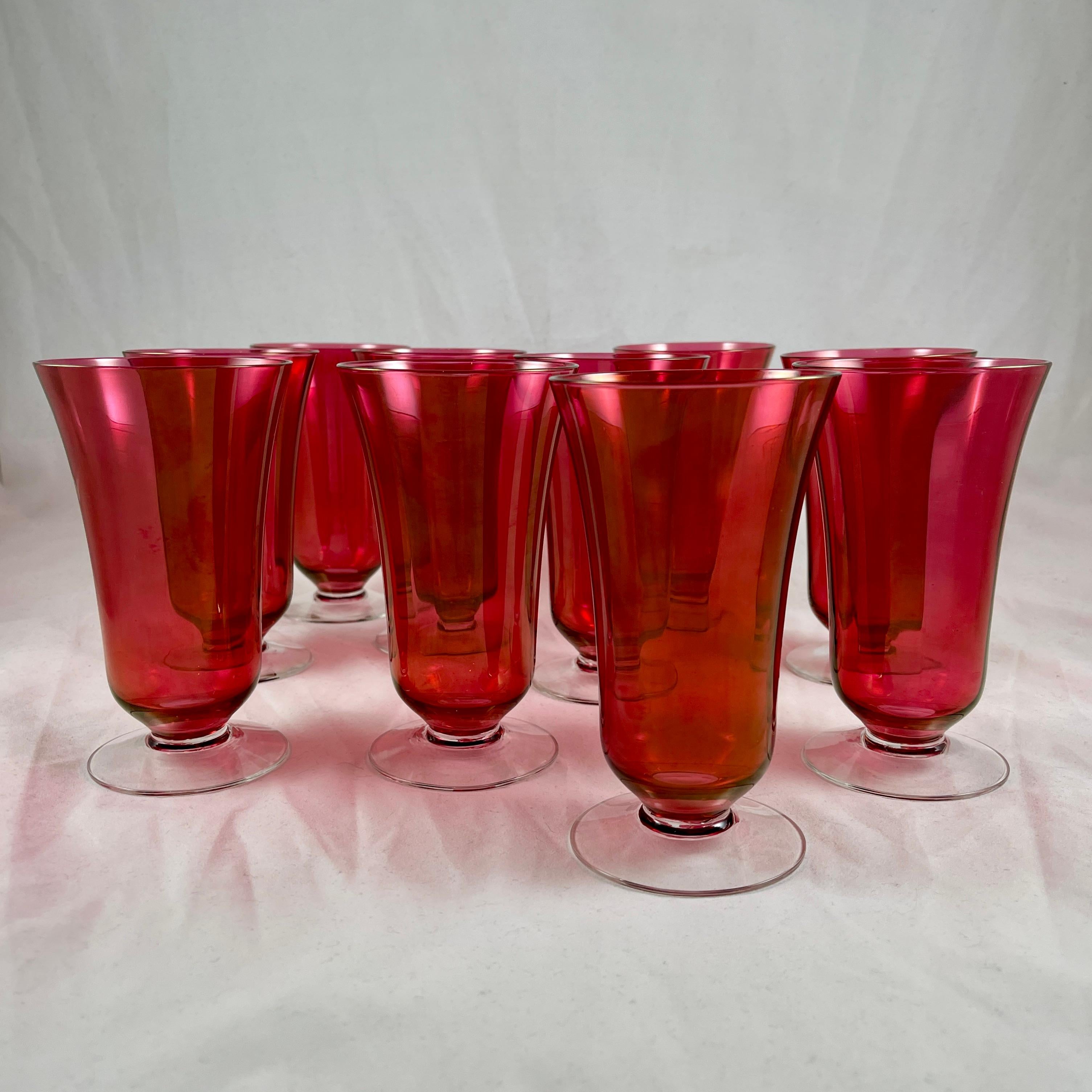 Ein Satz von zehn eleganten Cranberry-Glas-Fußbechern aus der Zeit des Art déco, um 1930.
Wunderschöne Farbe!

Die Becher zeigen ein breites optisches Muster um den Cranberry geflashten Körper mit einem farblosen Fuß. Die Größe ist als Eistee