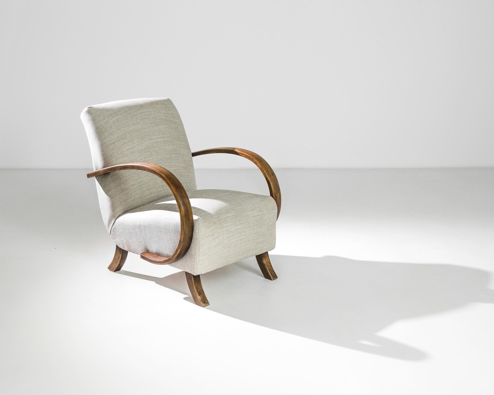 A Modern armchair by Czech furniture designer J. Halabala. Made in the 1930s, the eye-catching silhouette and comfortable design has an enduring appeal. Influenced by Mid-Century Modern and Art Deco design, a deep upholstered seat upon curved wooden