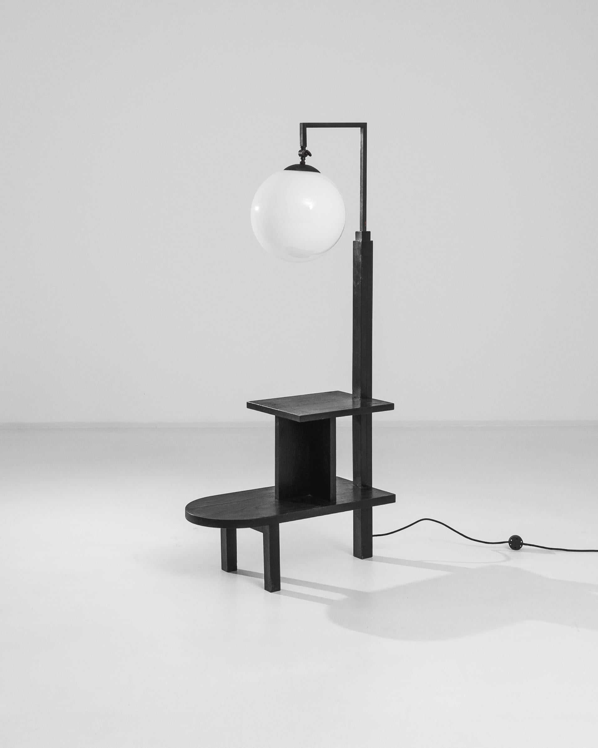 A modern floor lamp created circa 1930 attributed to the Pioneer of Czech Industrial Design Jindrich Halabala. The original outlines of this vintage piece are shaped by a black patinated wooden base on square feet, an iron angular pole and a round