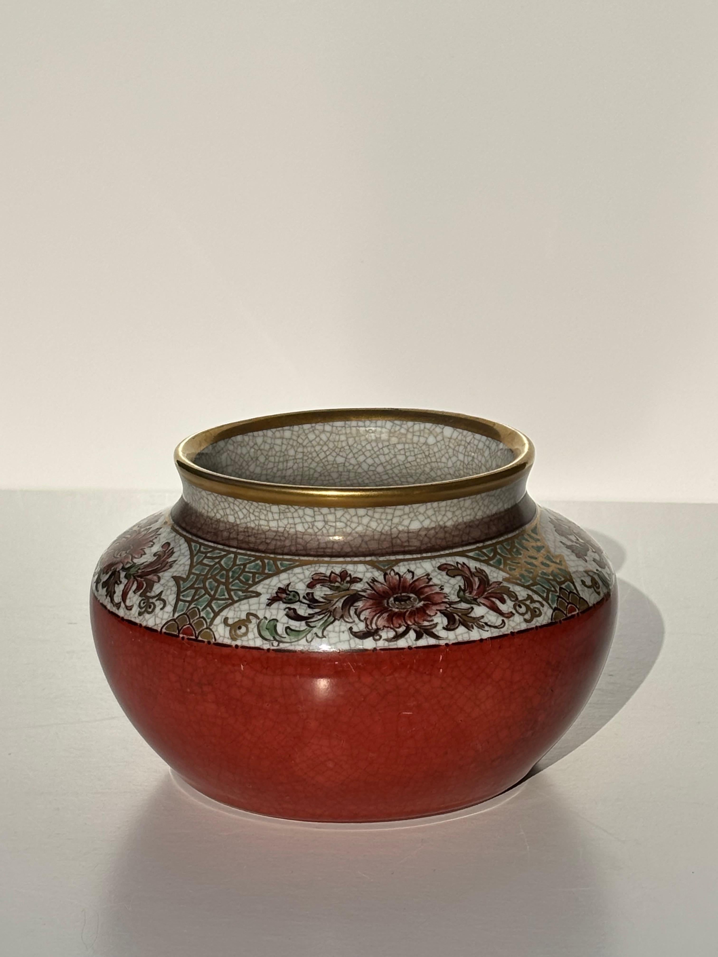 Vase art nouveau danois en porcelaine de terre cuite à glaçure craquelée rouge et blanche avec une bande décorative complexe dorée, bordeaux et verte peinte à la main autour du sommet. 
Produit par Dahl Jensen dans les années 1930. 
Belle condition
