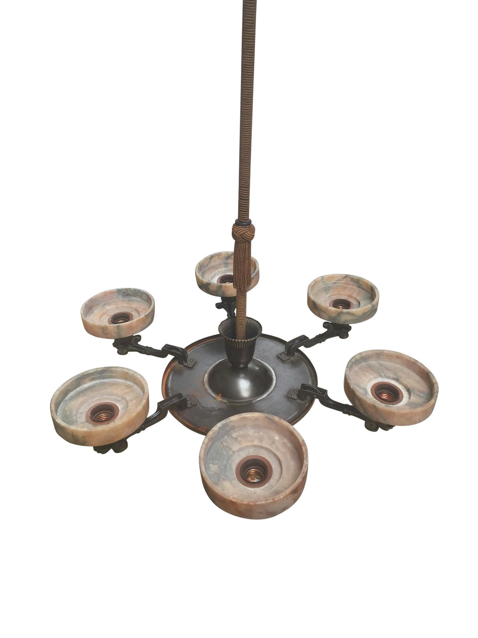 A beautifully crafted Danish Art Deco chandelier made in the 1930s. Comprised of bronze arms, canopy, & column, with rope trimming. The candle-style collars are marble with a nice pink hue. Each bobeche holds a single bulb. There are 6 sockets in
