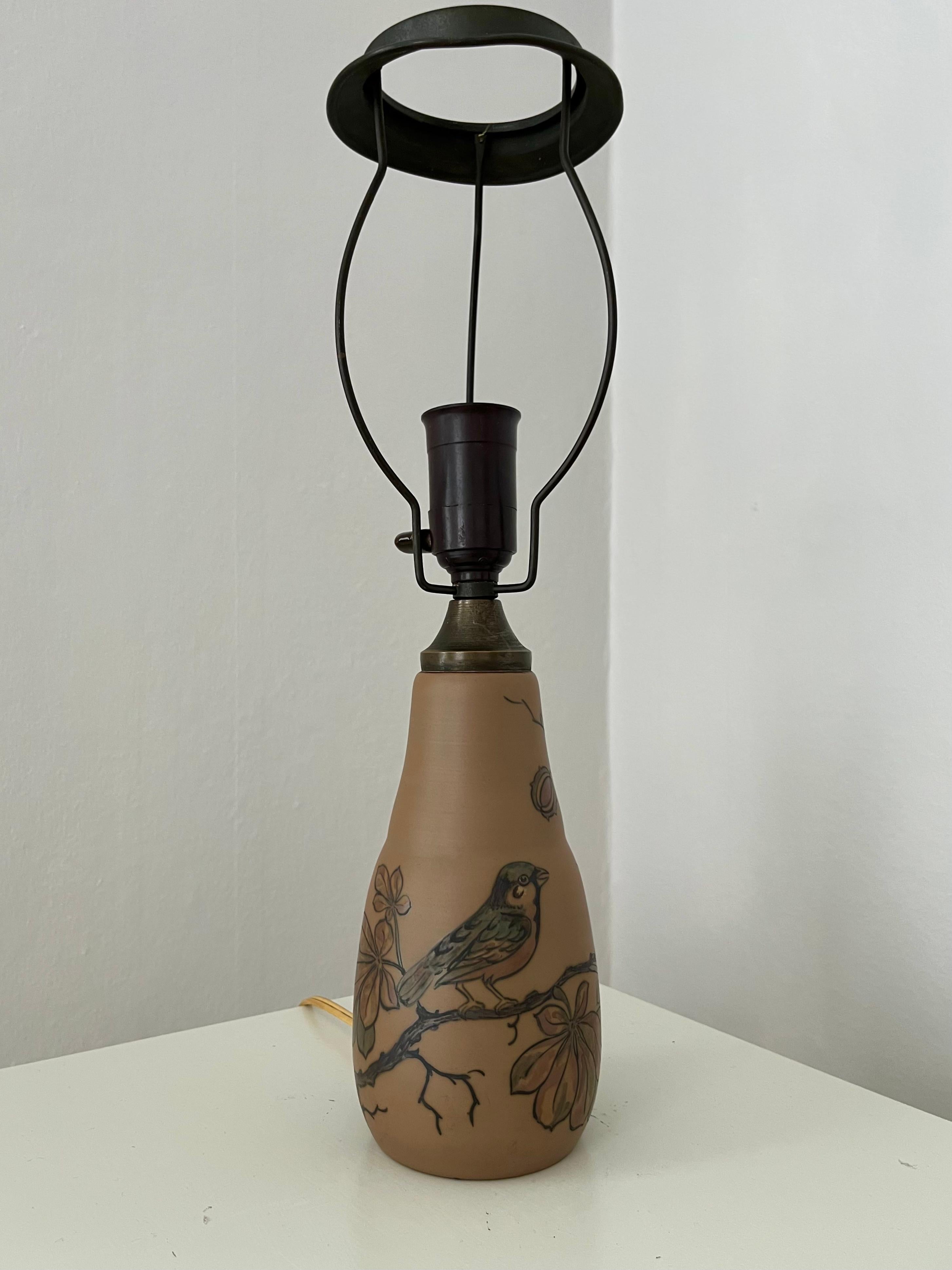 This Art nouveau Danish ceramic smaller table lamp is hand decorated, made by L. Hjort ceramic factory on Danish island Bornholm that is famous for it's outstanding ceramic workshops. Hand decorated with a bird sitting on a branch and leaves in