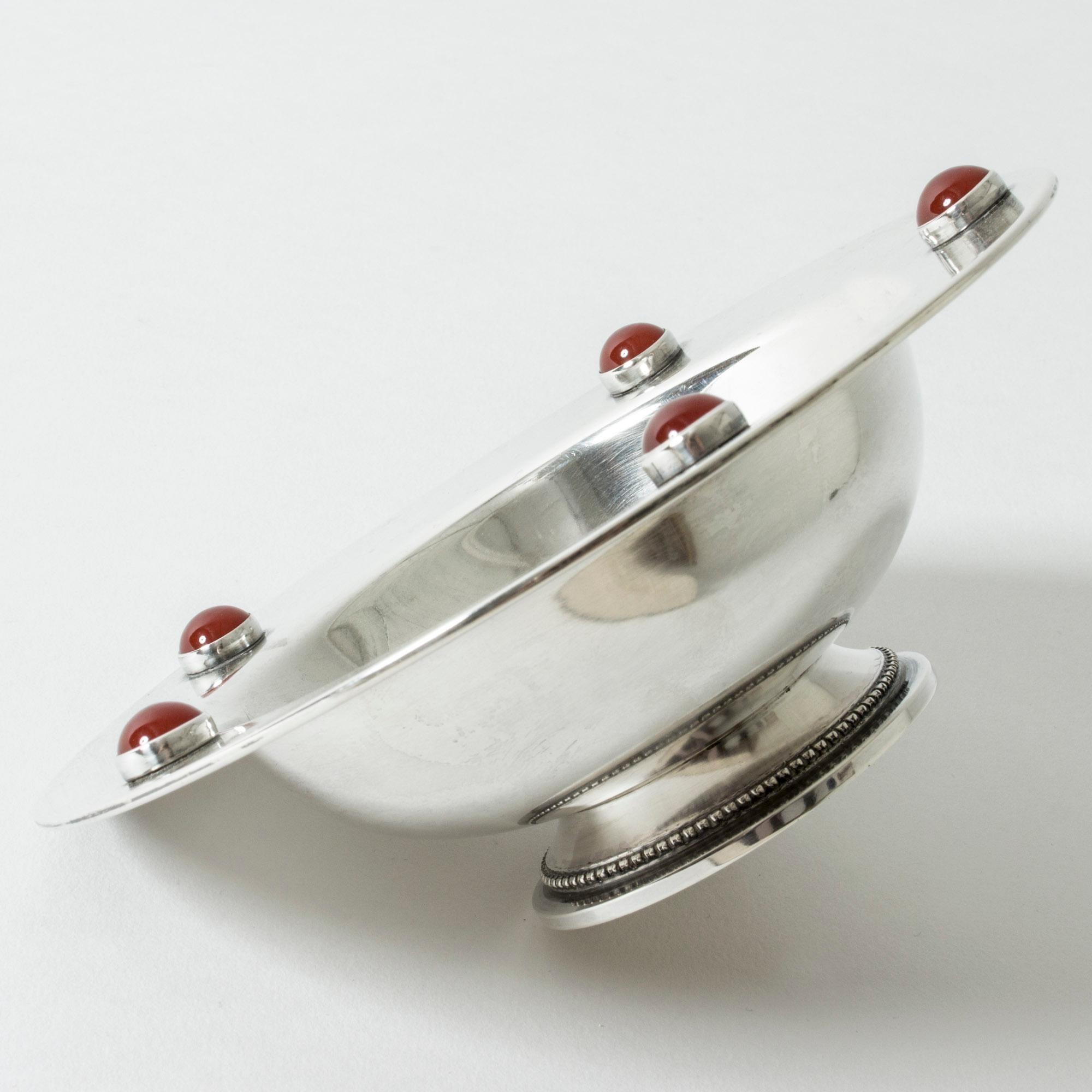 Elegant Danish midcentury silver bowl, in a smooth, streamlined design. Decorated with five round carnelian stones that contrast beautifully with the cool silver. Decorative pattern around the base.