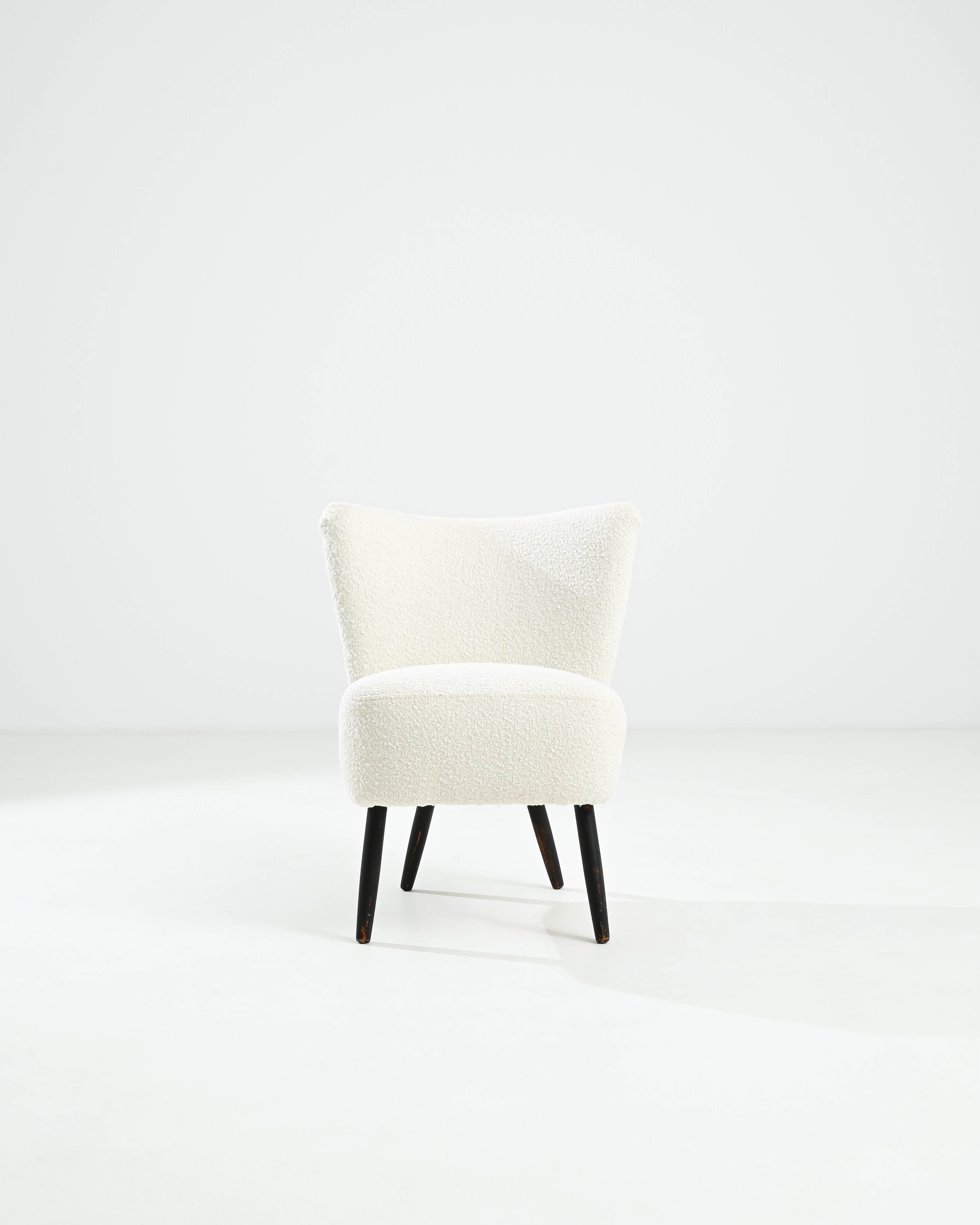 Discover the charm of the 1930s with this elegant Danish Upholstered Chair. Showcasing the best of Scandinavian design, this chair features a beautifully contoured back and plush, textured upholstery in a creamy-white hue. The sturdy, tapered wooden