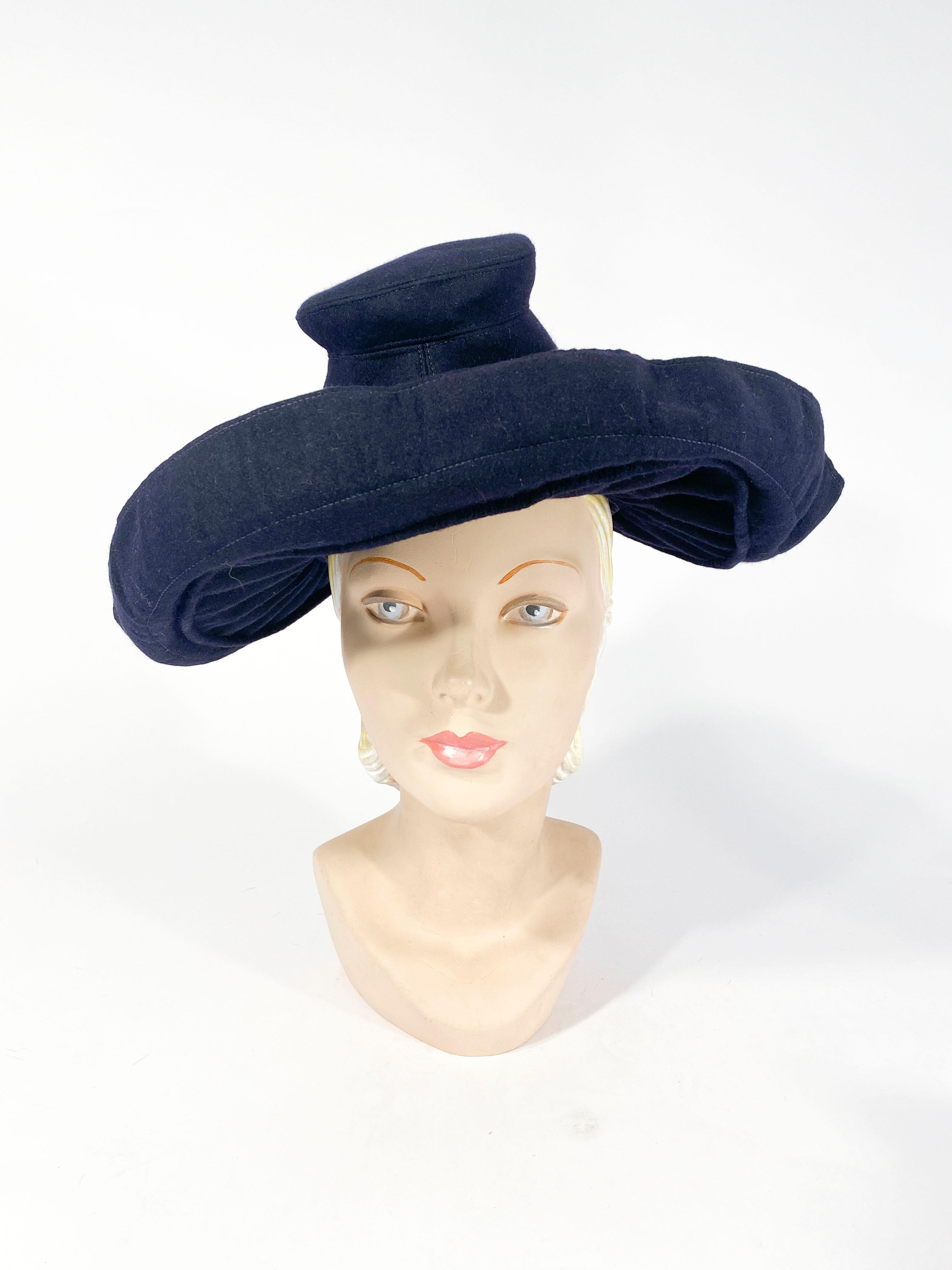 1930s Dark navy blue hat with a gathered wide brim that folds back at the edge lined with red contrasting gros-grain ribbon. The crown of this hat is hand-sculpted in a silhouette made famous by Adrian during the 1930s.