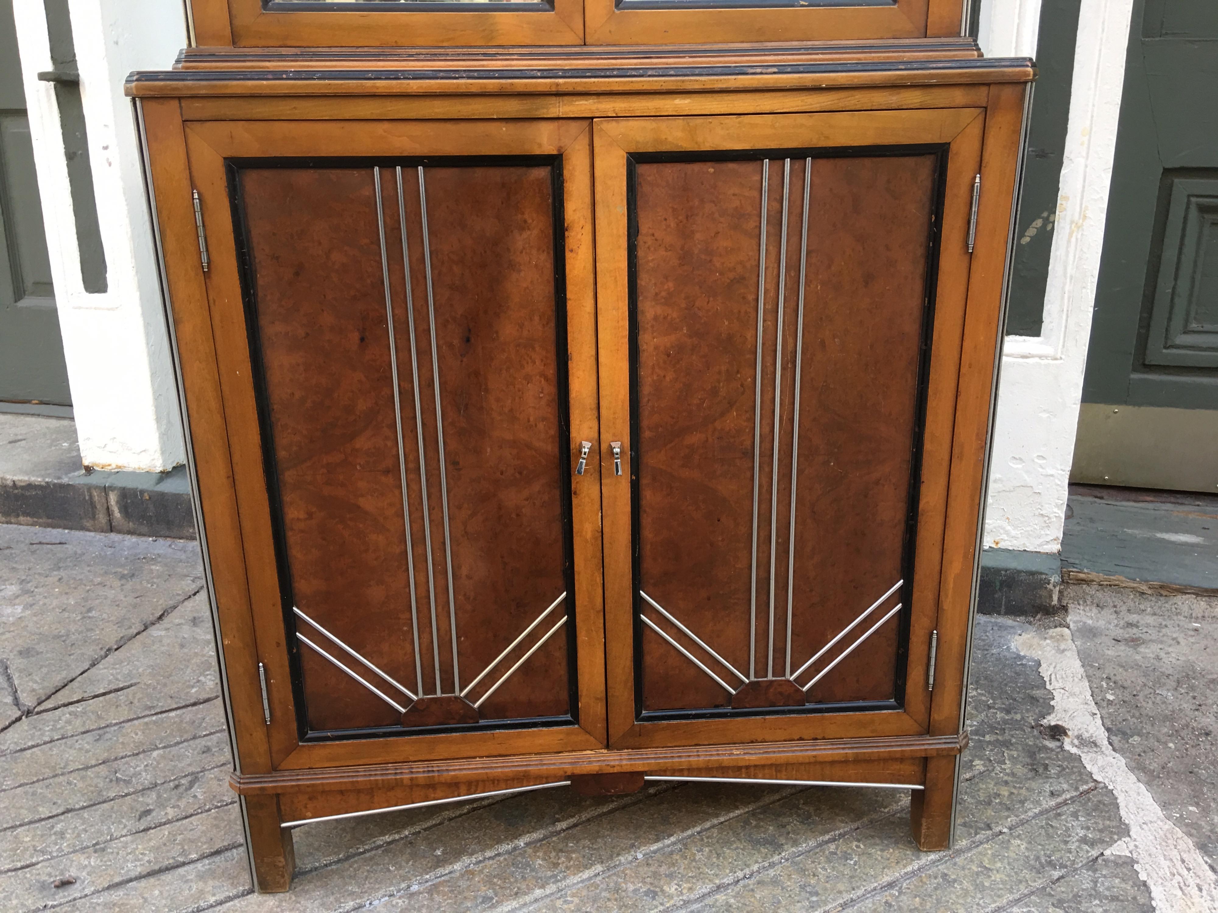 Very nice deco cabinet with mirrored top doors. Upper doors open to reveal two shelves. Lower doors are decked out with chrome trim and painted triangles. Very nice original condition. Perfect size for bathrooms, kitchens or compact spaces.