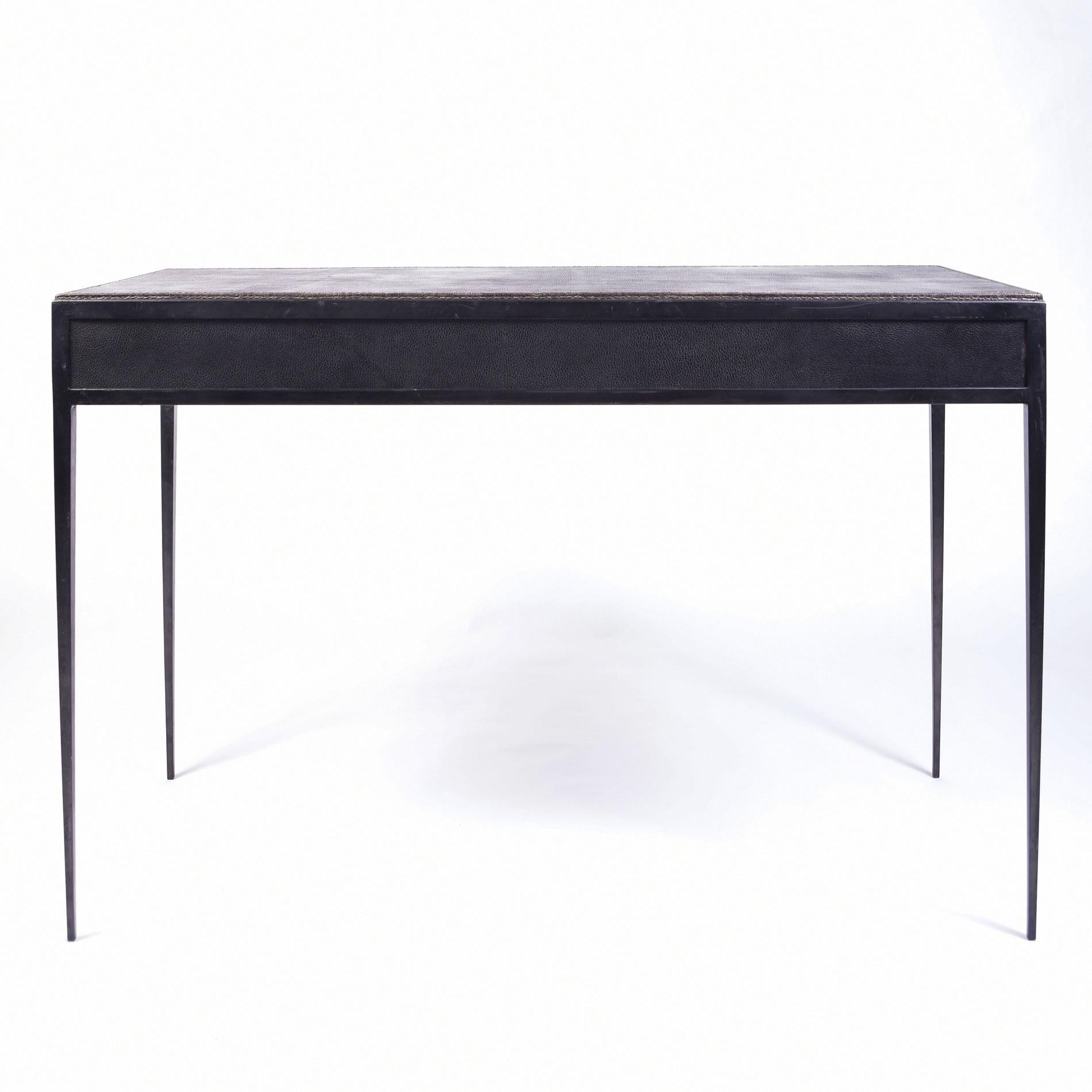 A desk of exceptional quality, demonstrating exactly the designer's mastery of perfectly balanced minimalist lines, with their tapered legs and precise detailing. Iron legs support the black/grey leather top with two cerejeira (Brazilian oak)