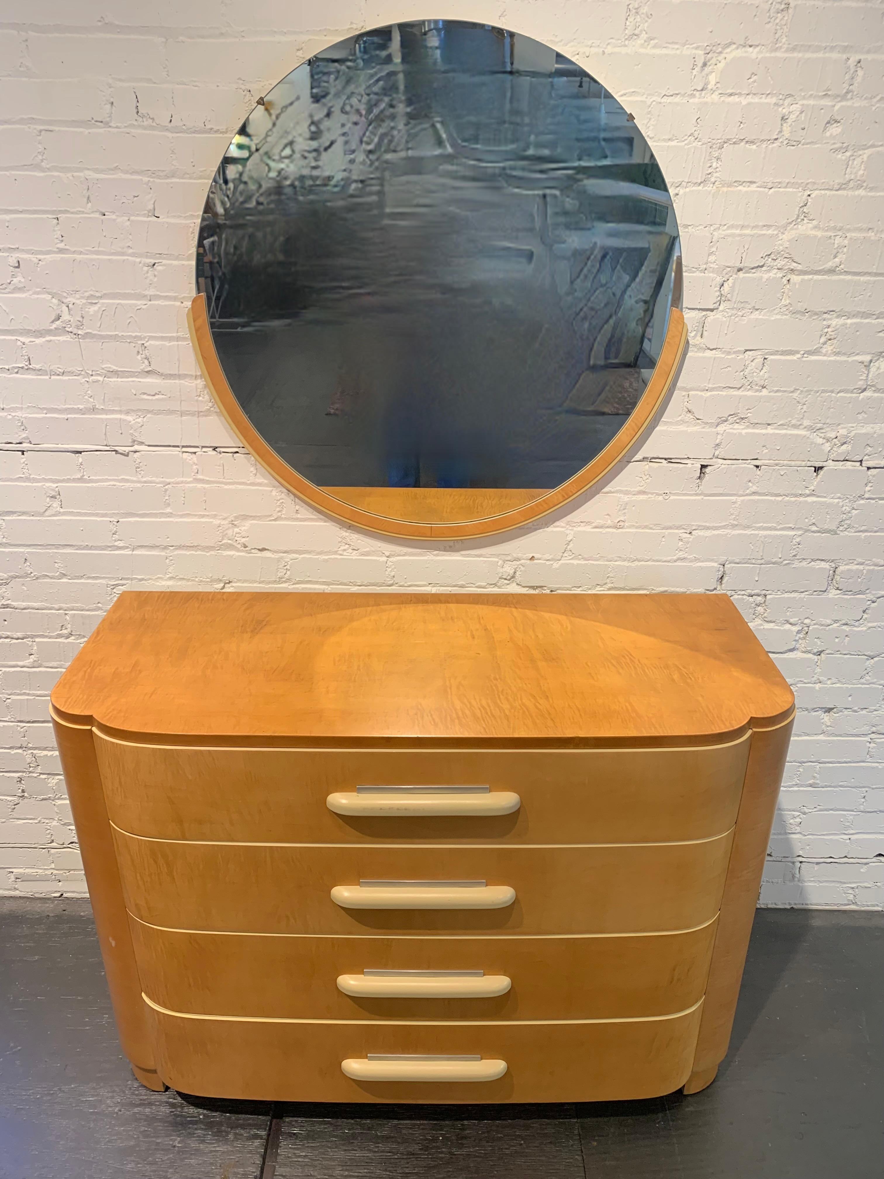 Splendido comò basso d'epoca dal design Art Déco con specchio rotondo di Donald Deskey (1894-1989) per Widdicomb, impiallacciato in acero con dettagli in alluminio. Maniglie e punti luce laccati color crema. Restauro di vecchia data, usato
