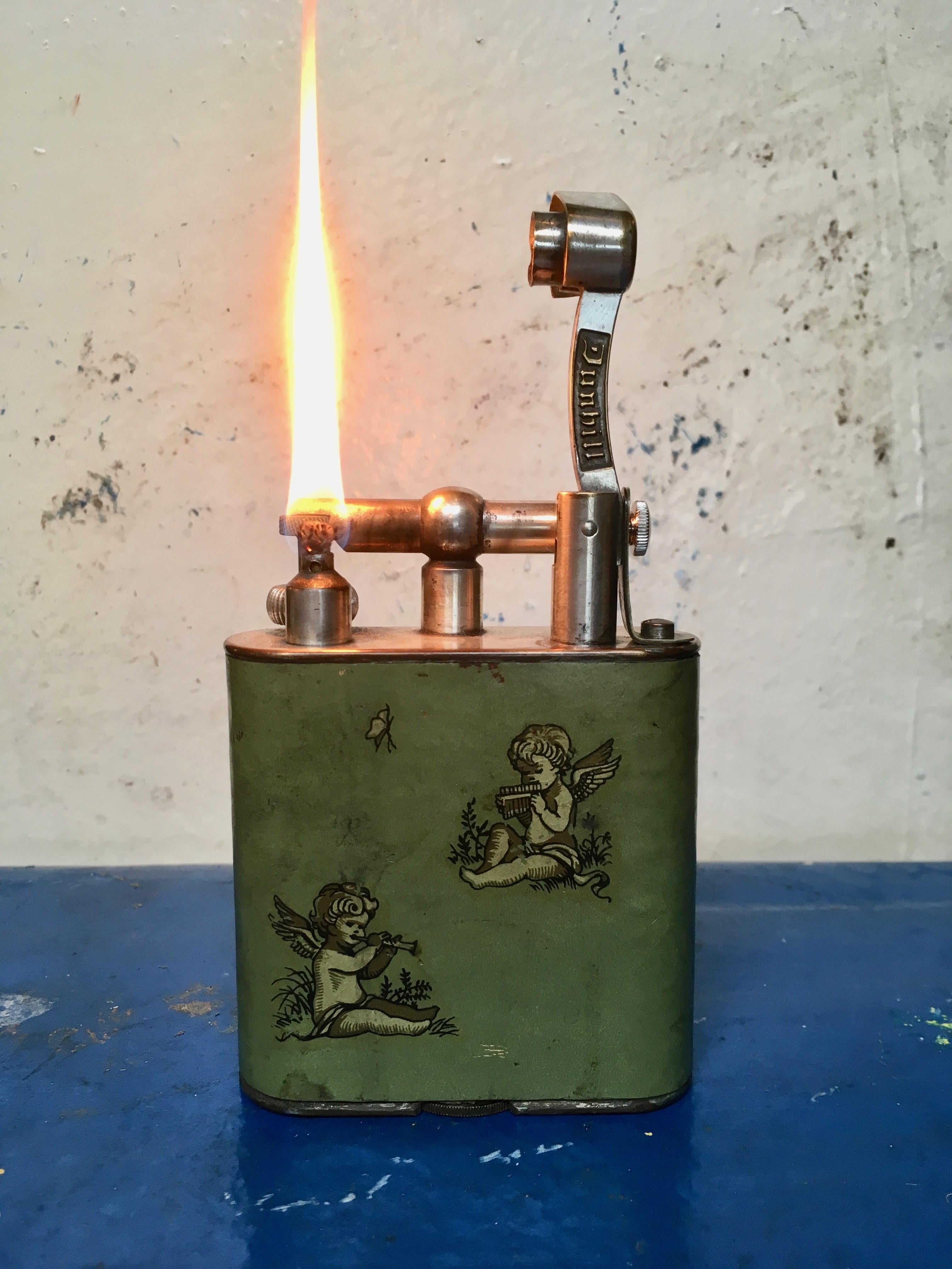 Stunning lighter made in the 1930s by Dunhill. Newly serviced. Green leather with cherubs in excellent condition. Flip top arm to reveal flame. Marked Dunhill on arm and on bottom side of lighter. Beautiful tabletop lighter. Works perfectly!

 