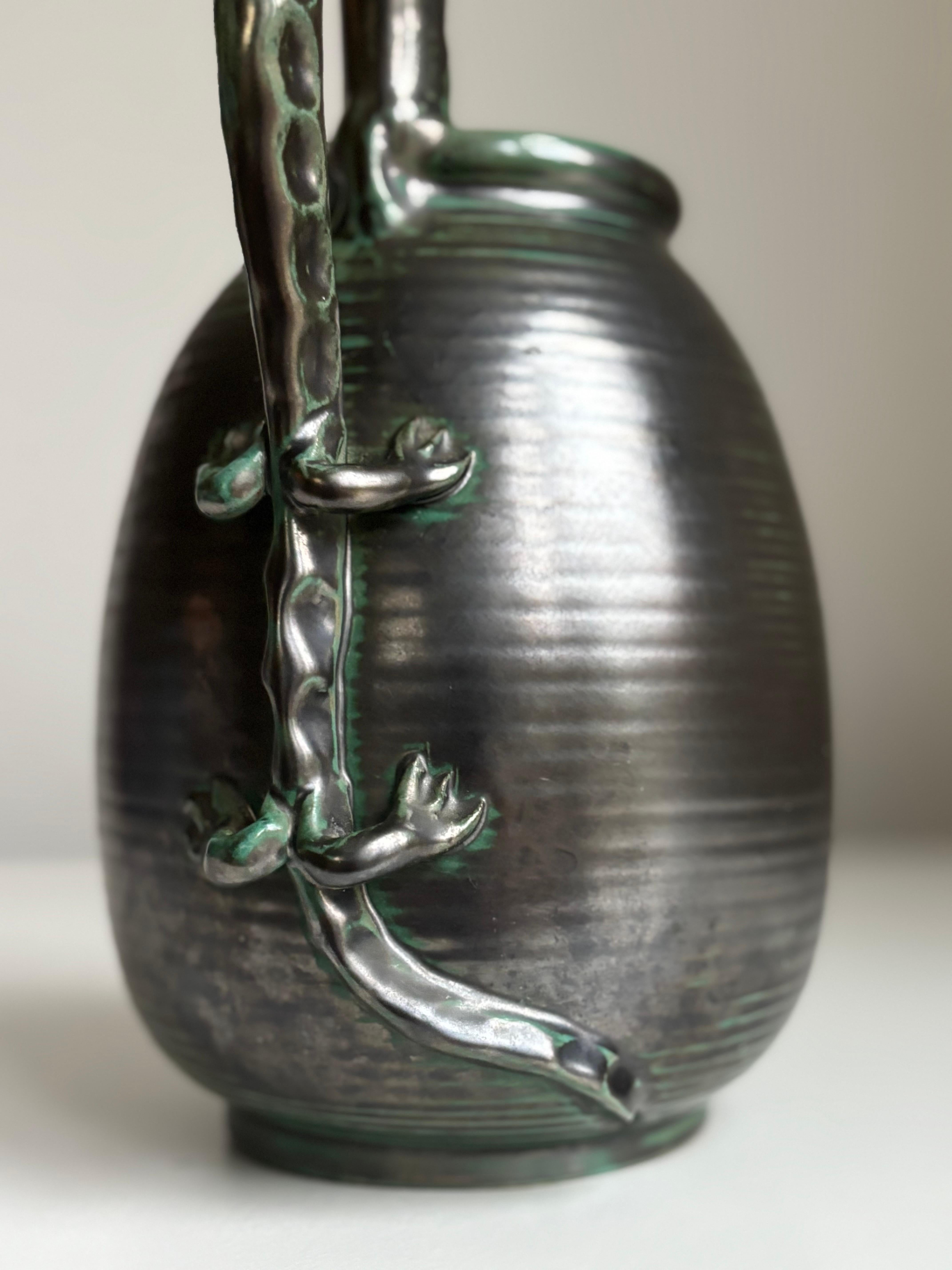 Vaso scultoreo in stile Art D�éco con grande manico a forma di lucertola realizzato dall'artista svedese Einar Luterkort (1905-1981) per Upsala Ekeby all'inizio degli anni Trenta. Lo smalto nero antracite e verde scuro aggiunge un'espressione