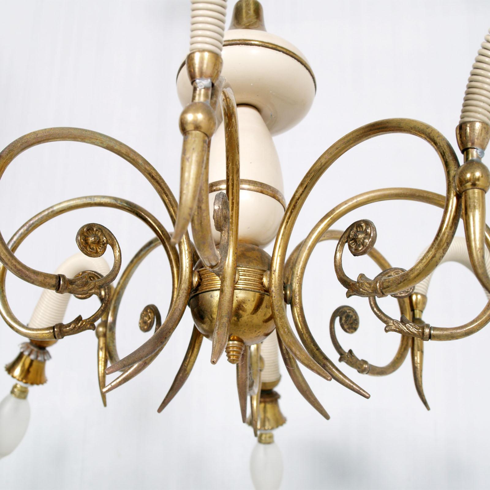 Italian Art Deco eight-arms chandelier from the 1930s. Curved brass arms are decorated in the final part with leafy and curly details. Each arm culminates in a spiral lacquered resin conical cover and eight original gold brass and ceramic