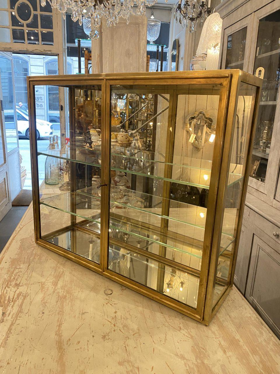 Gorgeous and presentable quality brass display cabinet from 1930s France. Art Deco style, with associated lock and key, 2 glass shelves and beautiful mirrored glass backing. The display cabinet was initally boutique inventory and is in very good