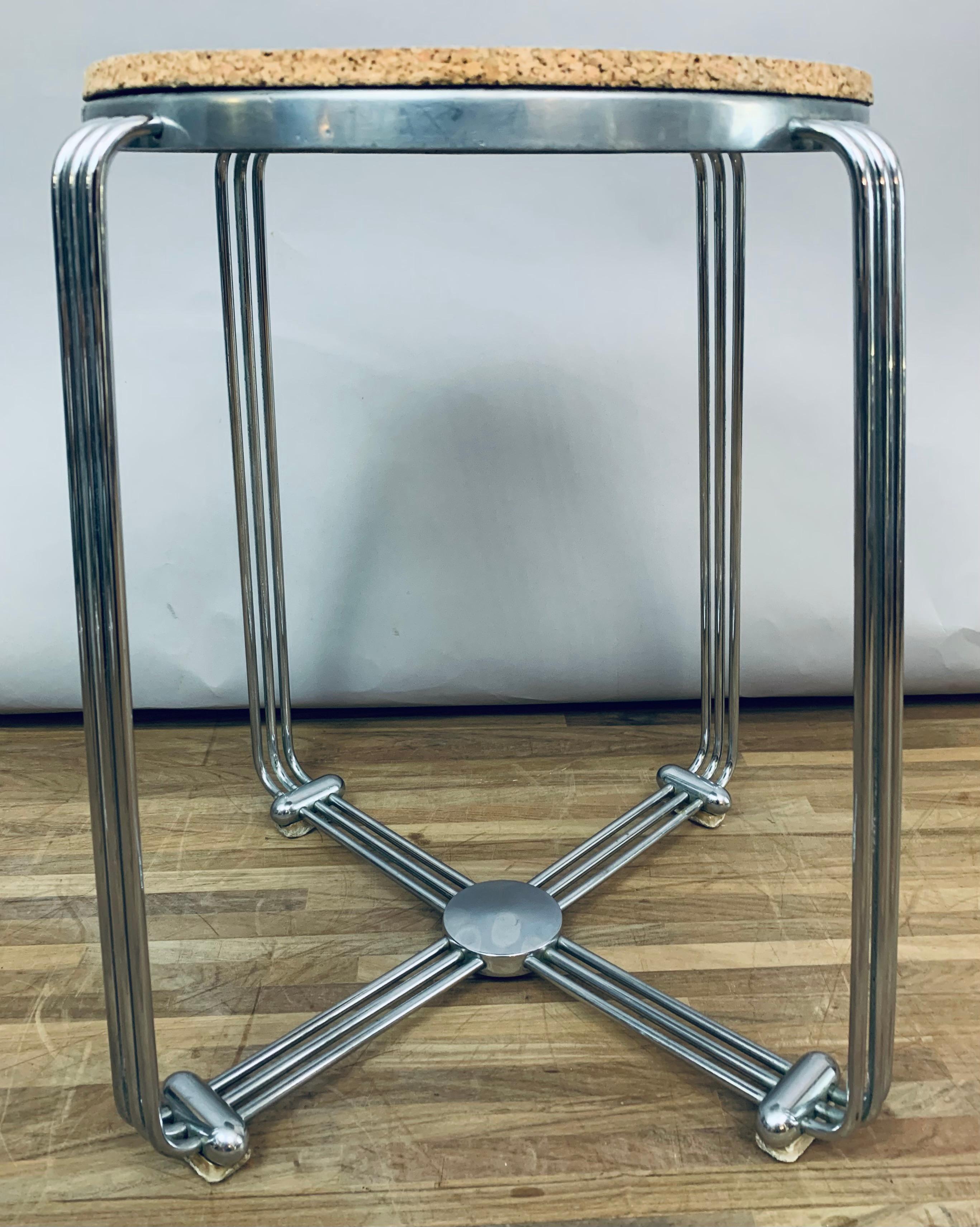 An English 1930s Art Deco stool made by Alpax with chrome tubular splayed legs, cast aluminium seat base and cork seat. The seat is held in place with four chrome legs constructed from three chrome tubes which form the legs and base. The legs sit on