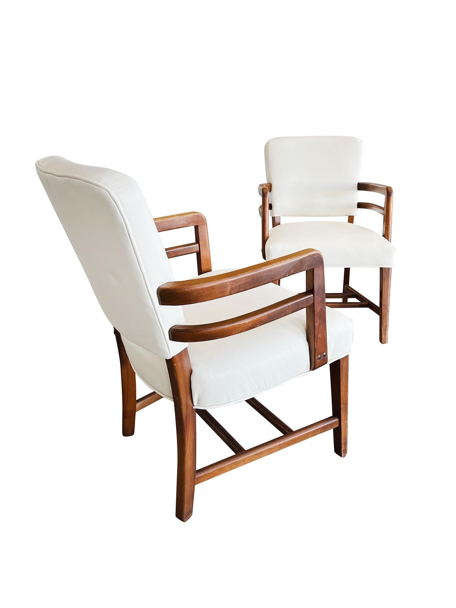 Exquise paire de fauteuils Art Déco anglais, fabriqués dans les années 1930 en bois de hêtre. Les chaises ont été récemment retapissées en cuir blanc huître, qui s'harmonise parfaitement avec les tons chauds du bois. Le travail du bois est