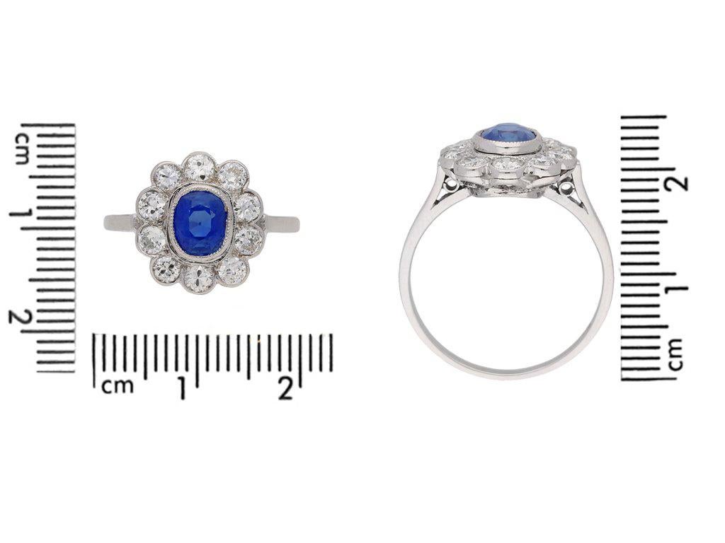Art Deco Kashmir sapphire and diamond cluster ring. Centrally set with a cushion shape old cut natural unenhanced Kashmir sapphire in an open back millegrain and rubover setting with an approximate weight of 1.20 carats, surrounded by a single row