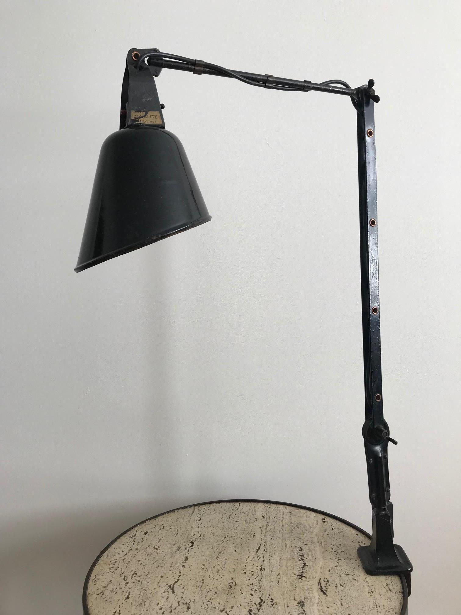 A very good example of a 1930s English Zonalite Walligraph Angle poise desk lamp. All original with just a few rust marks on the rim of the shade. The enamel and paint are original. The light fixes onto the desk by tightening the clamp and is easily