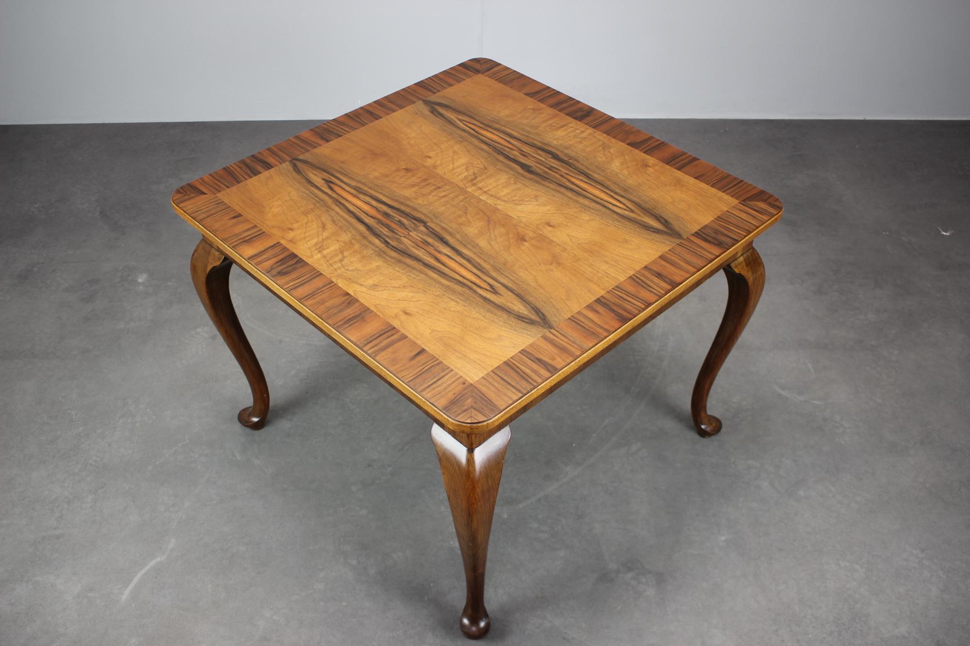 Cette table d'appoint carrée Art déco européenne des années 1930 incarne l'élégance géométrique et le savoir-faire raffiné du placage de l'époque. Conçue avec des pieds courbés et un cadre en placage de noyer, cette pièce reflète les traditions de