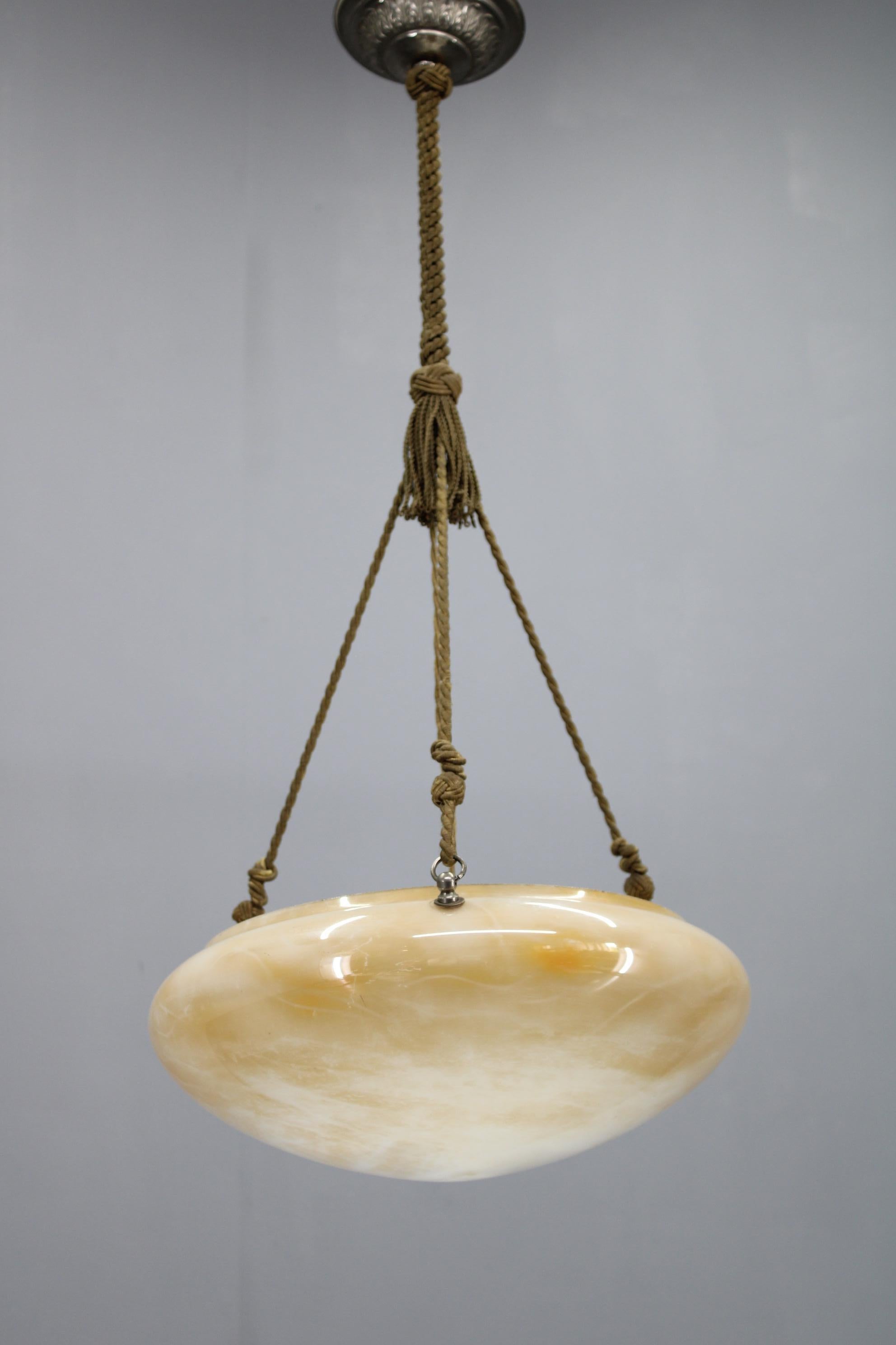 Questa straordinaria lampada a sospensione europea degli anni '30 rappresenta un ponte tra la fase finale della Secessione e la geometria emergente della prima Art Deco. L'apparecchio è caratterizzato da un paralume in vetro caldo in stile alabastro