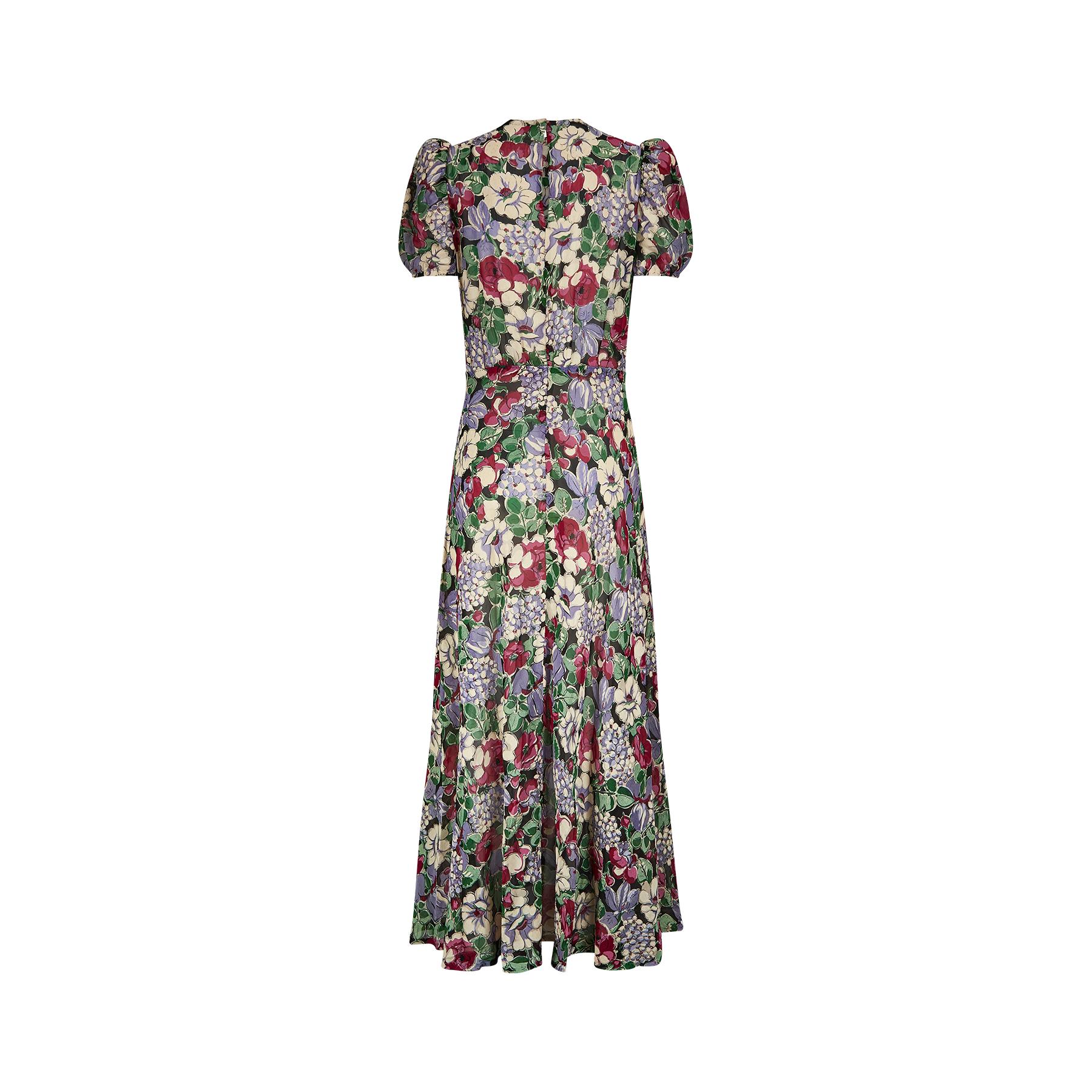 This is an exquisite example of 1930s fashion made from a wonderful floral cotton organza or stiffer georgette fabric. The colourful floral print showcases a mix of hydrangeas and old roses in lilacs, greens and pinks set against a midnight