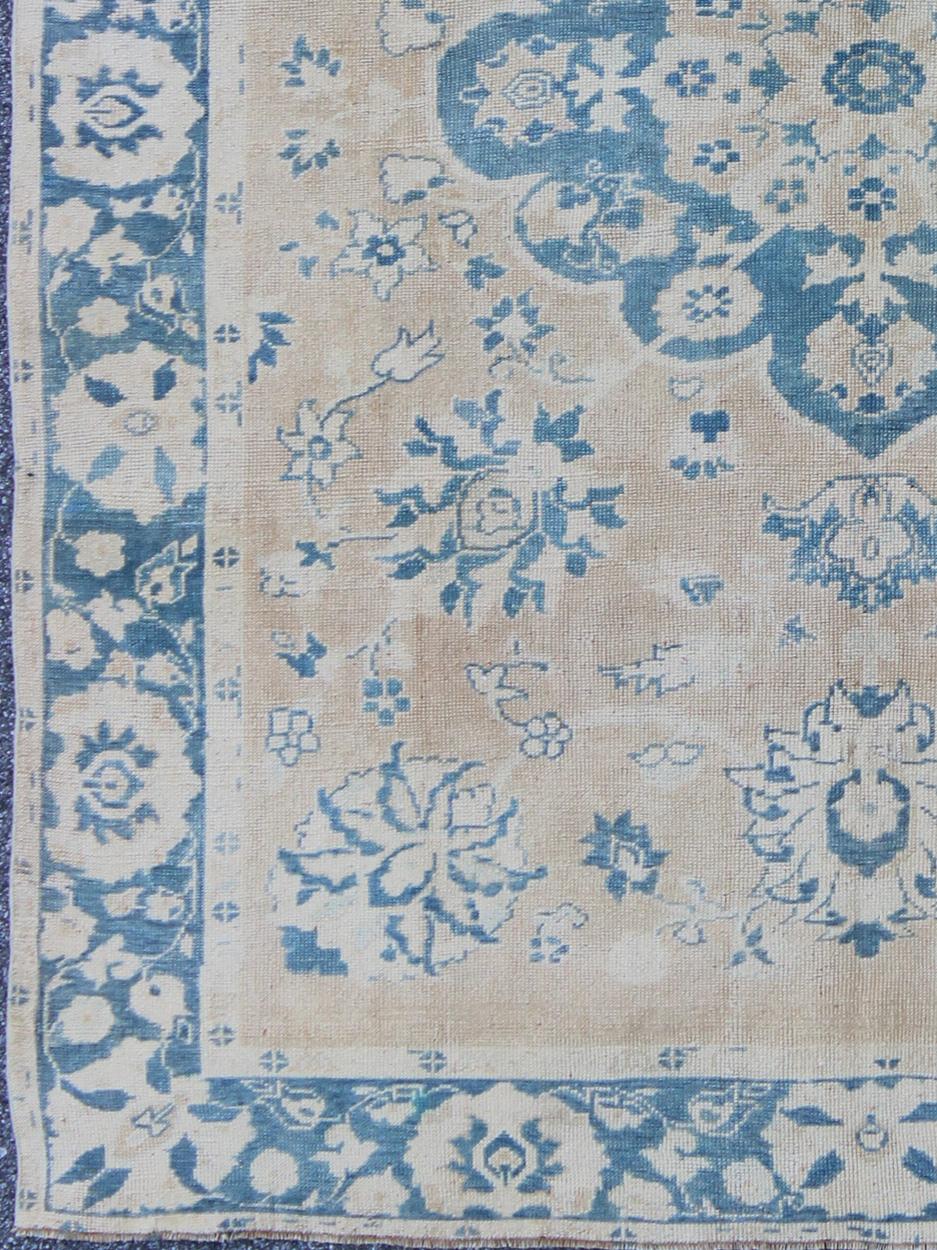 Handwoven in Turkey, this vintage Oushak rug features a large-scale medallion and floral bouquets. The butter yellow background is elegantly decorated by a variety of medium blue colors, which adds depth to this beautiful rug. Other colors include