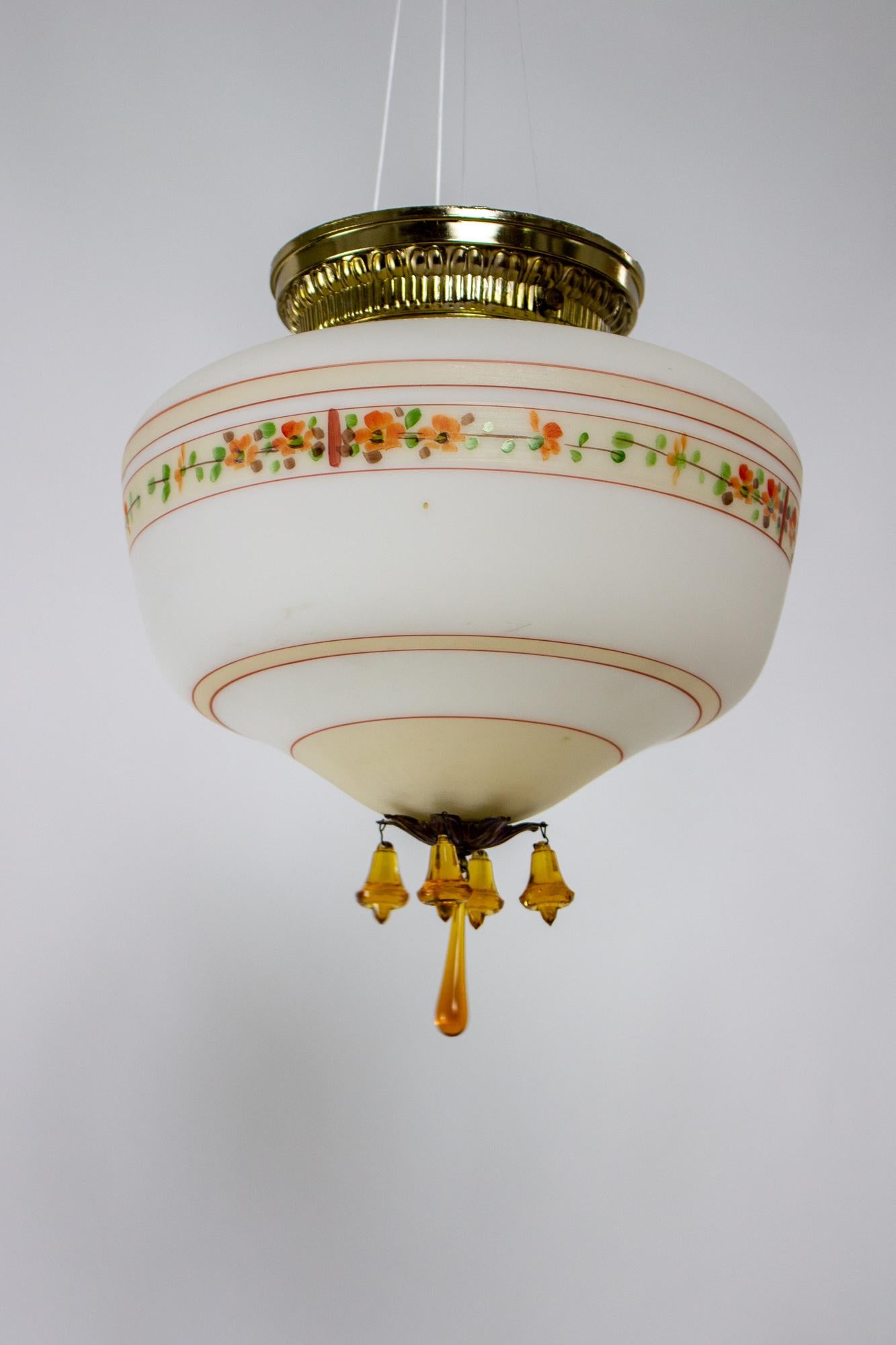 Schoolhouse light with a twist! Flush mount fixture, glass is painted with concentric circles and a ring of orange flowers. The bottom rosette holds a cluster of amber crystals.

Material: Glass,Metal
Style: Traditional,Art Deco
Place of Origin: