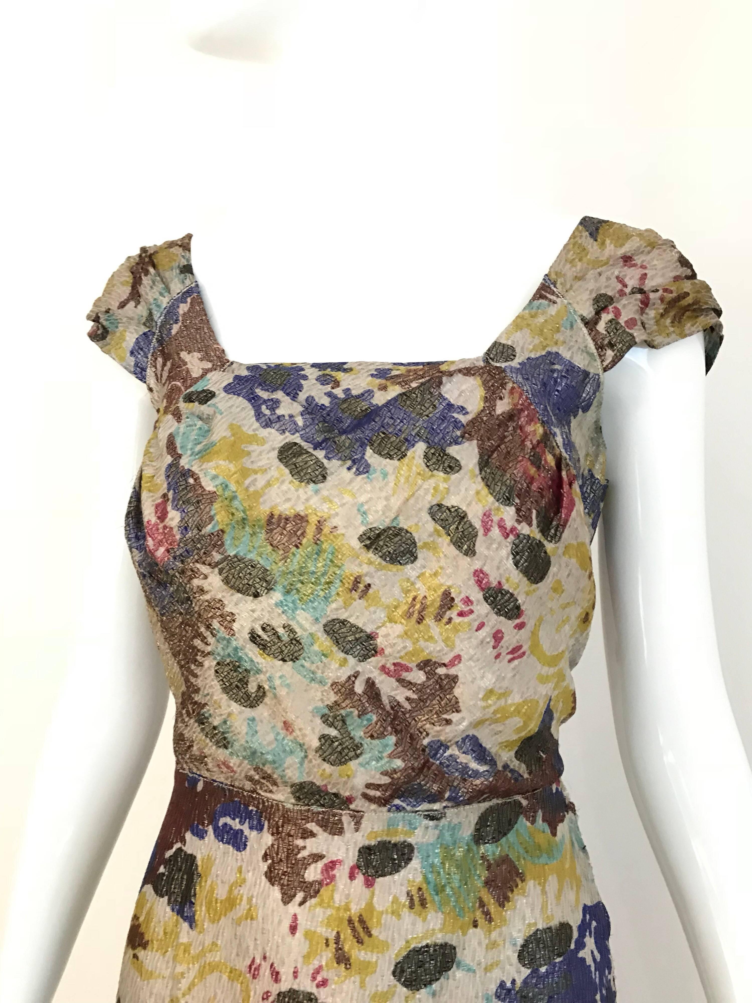 Elegant 1930s Silk lamé floral print in brown, mauve, blue, yellow and green.  Dress has cap sleeves with V shape exposure.  Dress has snap on button on the side. 
Perfect for downton abbey summer cocktail party.  Size: 4/6
Bust: 34 / W 27/ H 36” /