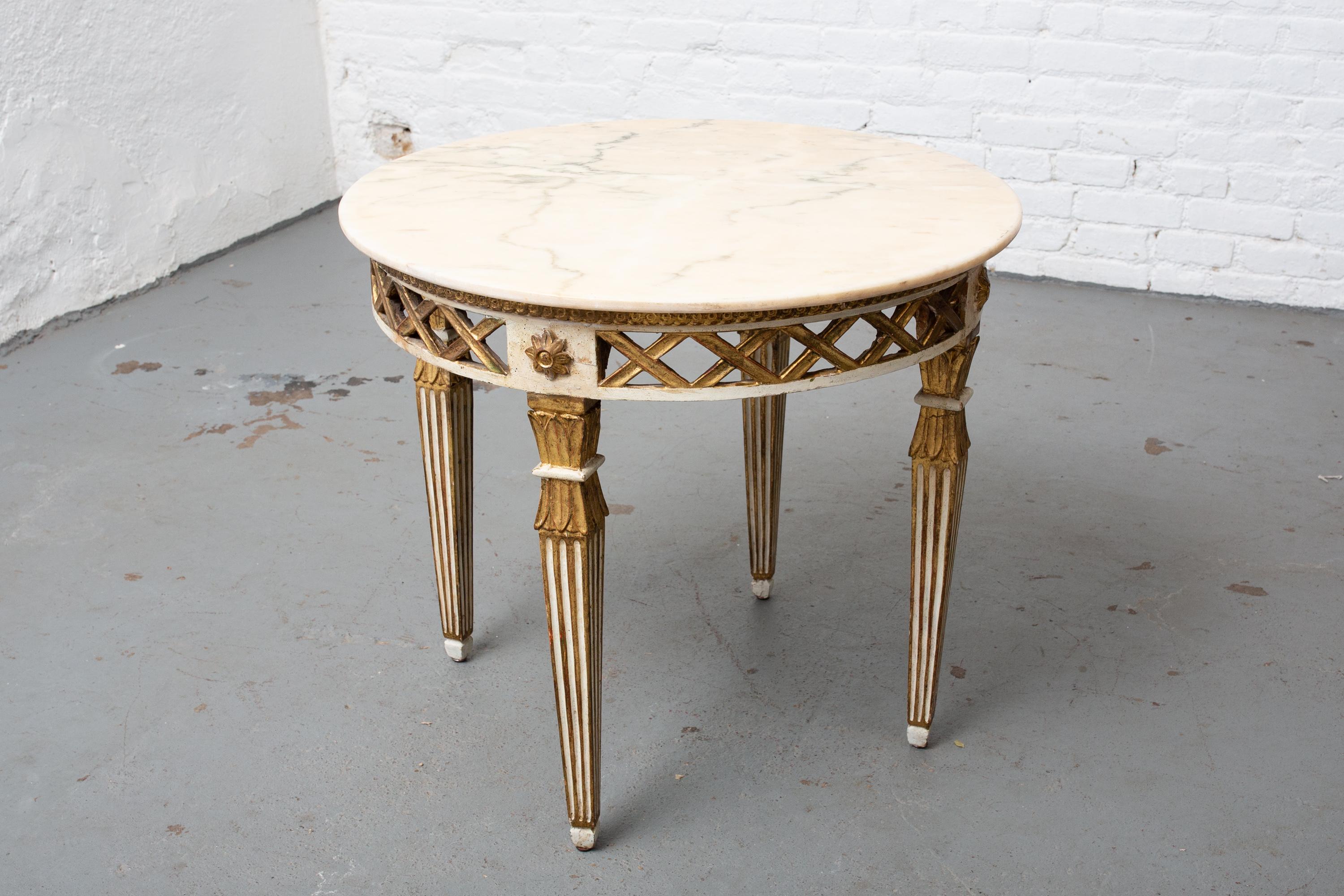 1930s Italian parcel gilt carved wood side table with marble top and fluted and tapered legs. Wood is well patinated. Sturdy.