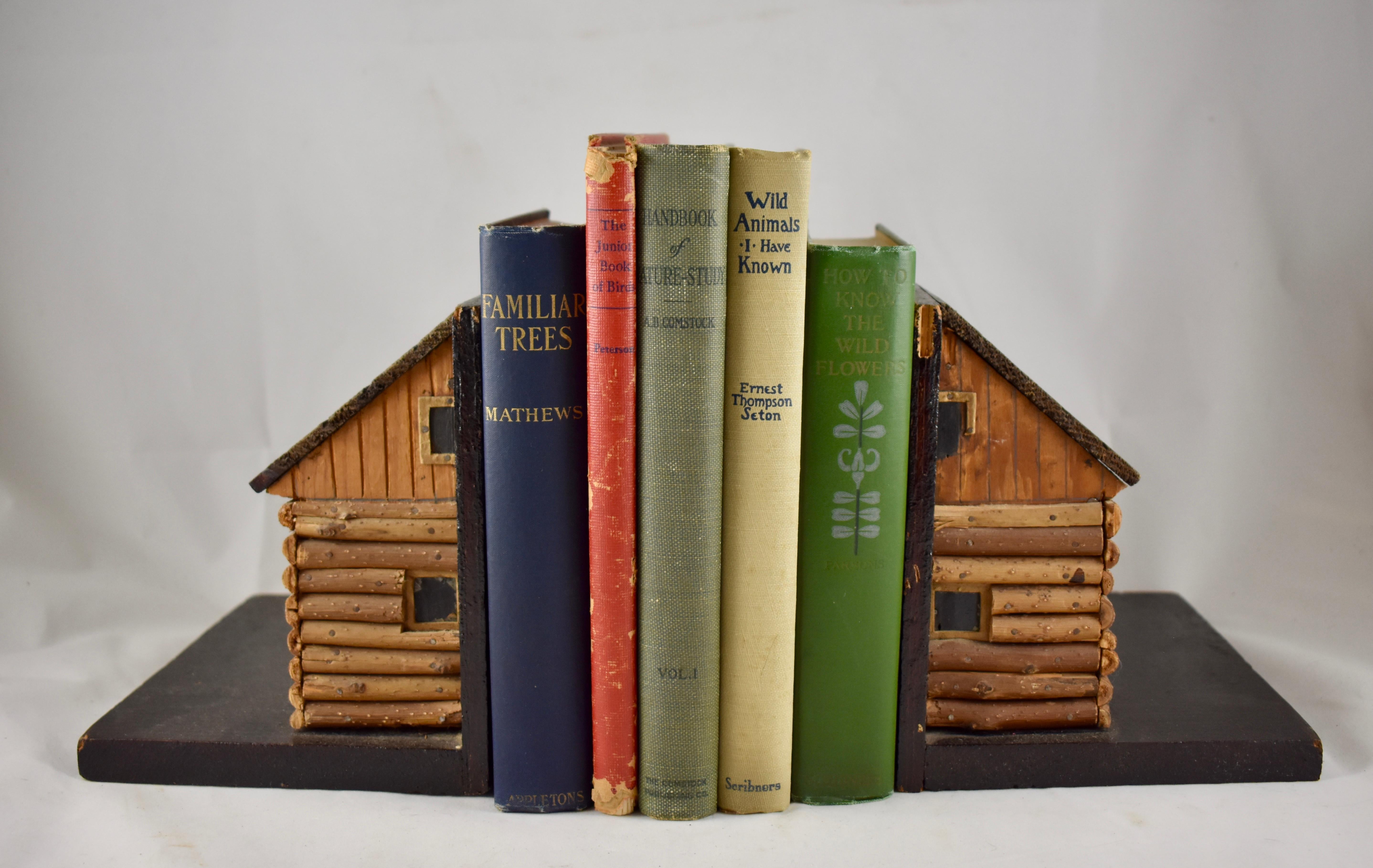 A rustic pair of handmade bookends, formed as log cabins, circa 1930s-1940s.
Crafted with great detail from found wood, cut tree branches, painted cardboard and small nails. A great piece of Folk Art suited for a boys room, den, or summer