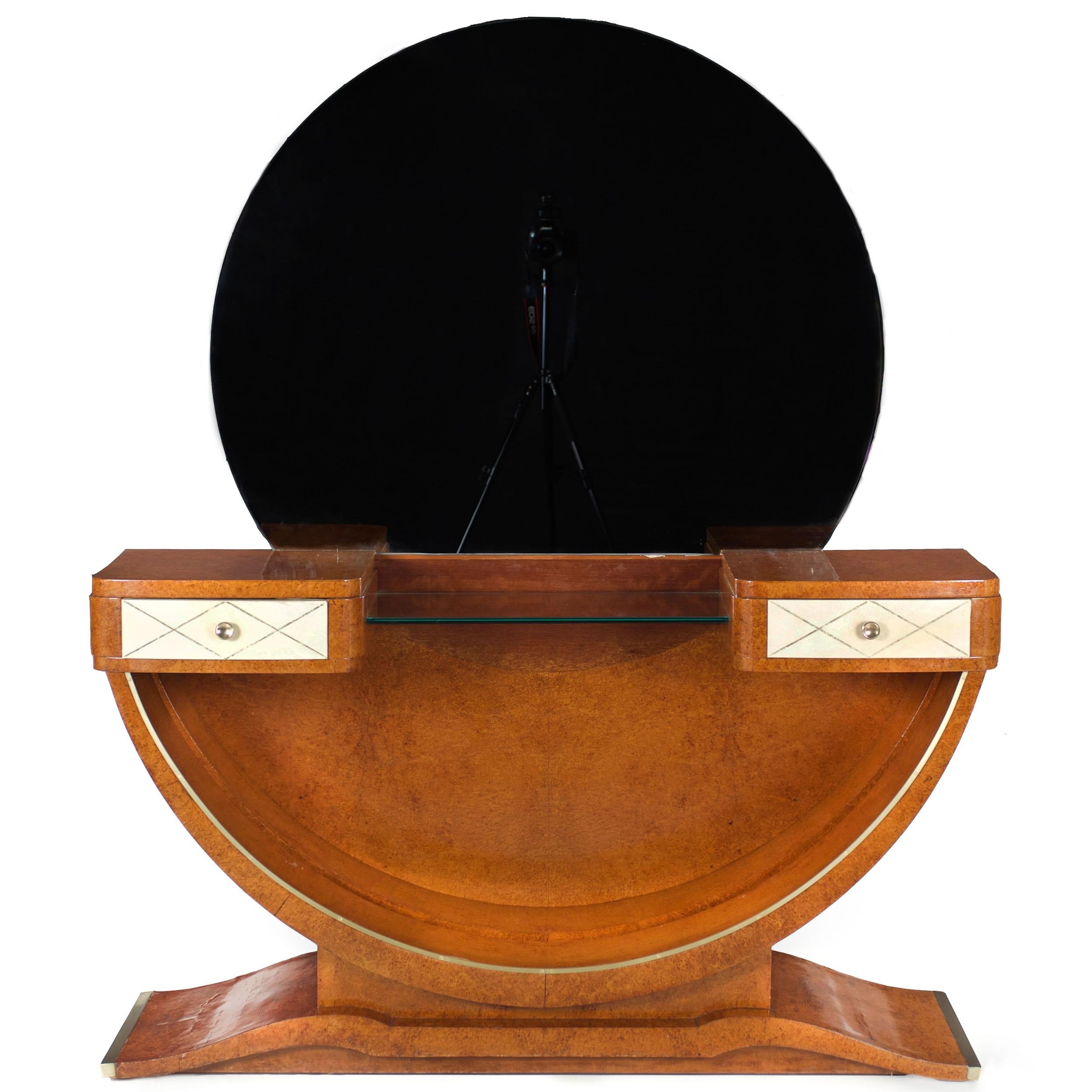 A rich and wonderful design from the Art Deco period, this dressing table features a large circular mirror rising above a stepped surface hosting a pair of hand-dovetailed drawers dressed in lacquered goatskin with gilt stenciling around original