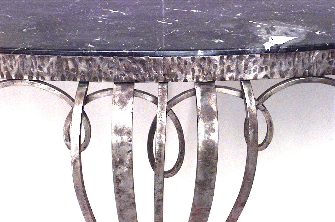 Console Art Déco en fer forgé avec supports avant et tablier à motifs de volutes, plateau en marbre noir et petite étagère à la base (Attribuée à RAYMOND SUBES).
