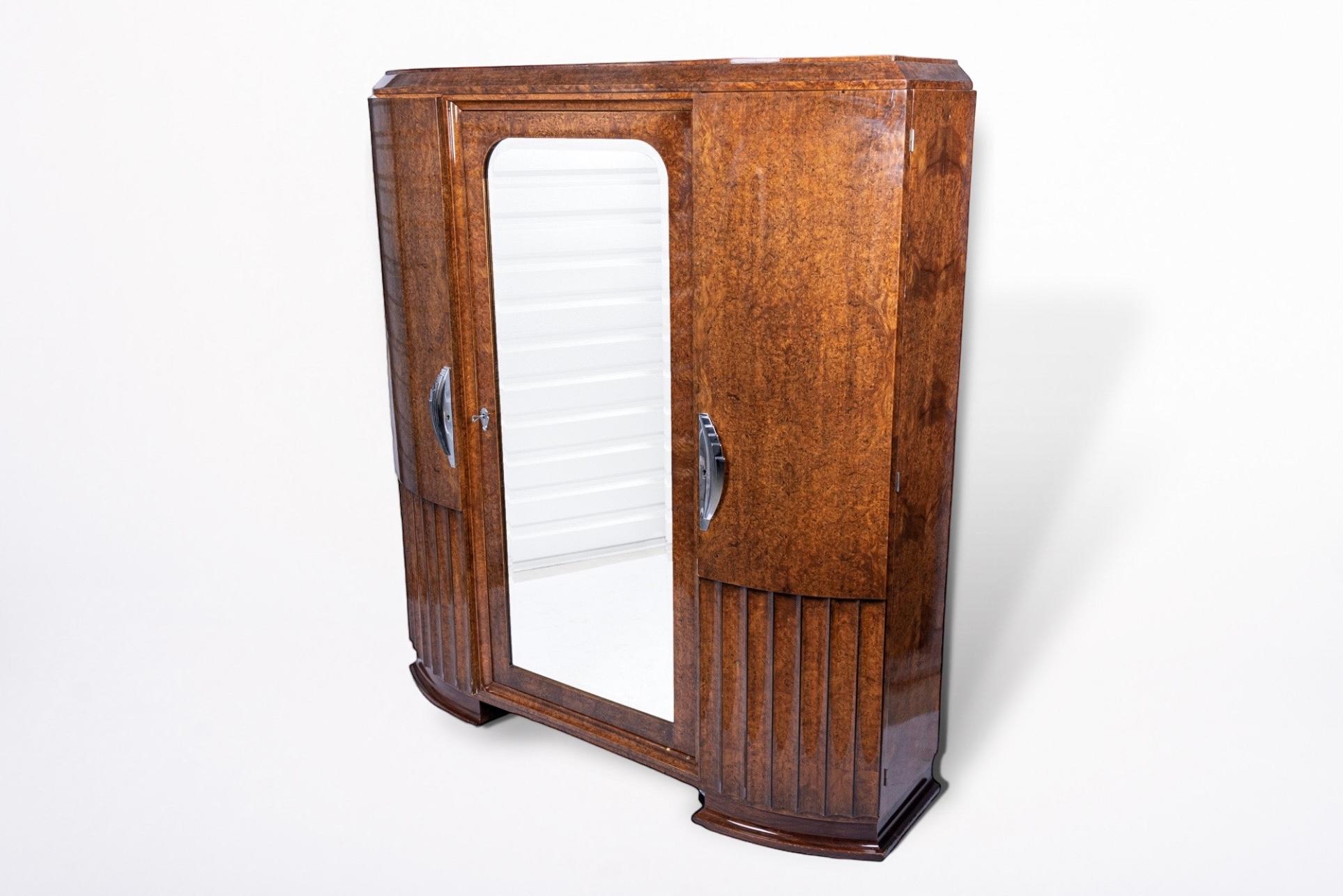 This incredible antique Art Deco lacquered wood armoire wardrobe cabinet is circa 1930. It is impeccably handcrafted from solid wood and Carpatian elm burl wood veneer with gorgeous patterning. It features finished interiors and beautiful curves