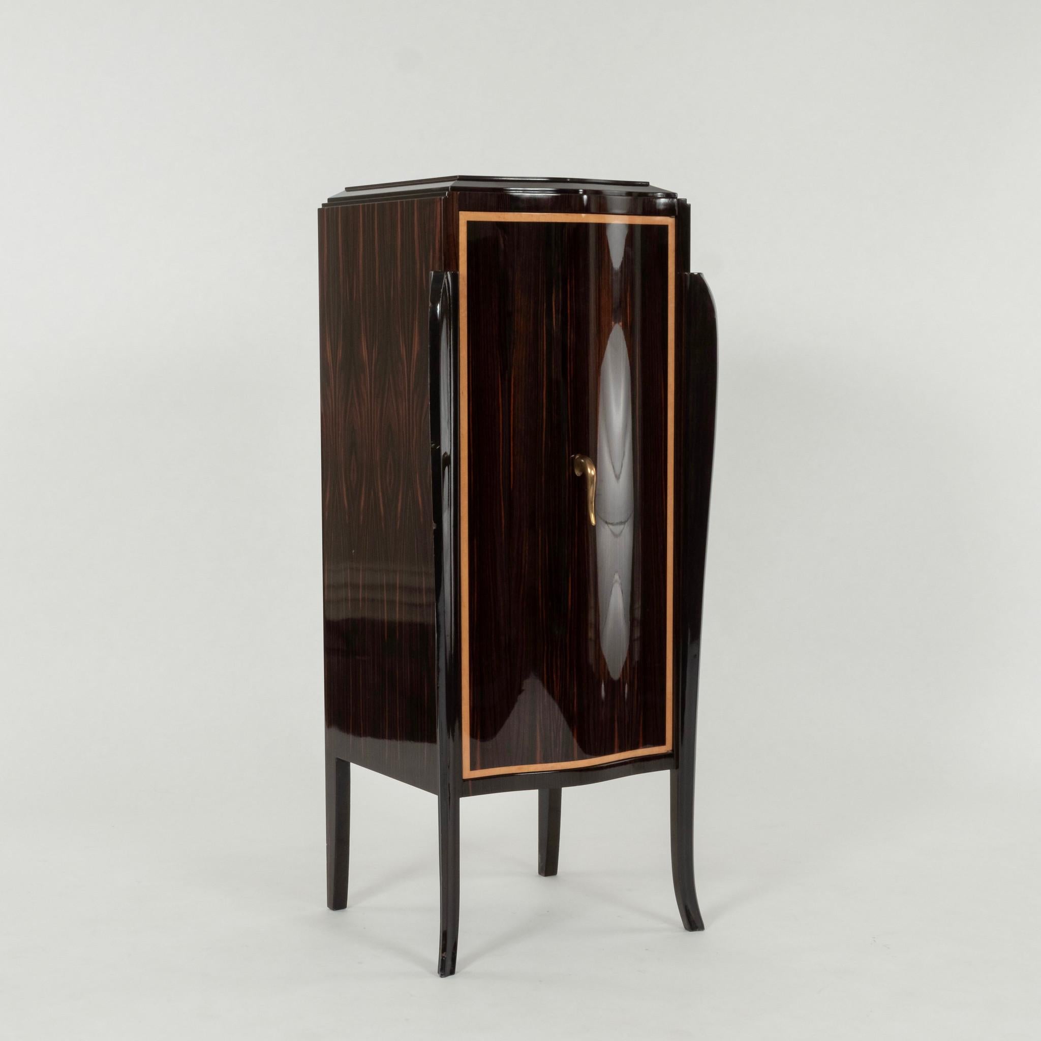 This exquisite French cabinet, attributed to the renowned French designer Jules Leleu, epitomizes the elegance and sophistication of Art Deco design. Veneered in rich Macassar wood, the cabinet features a luxurious lacquer finish that highlights the
