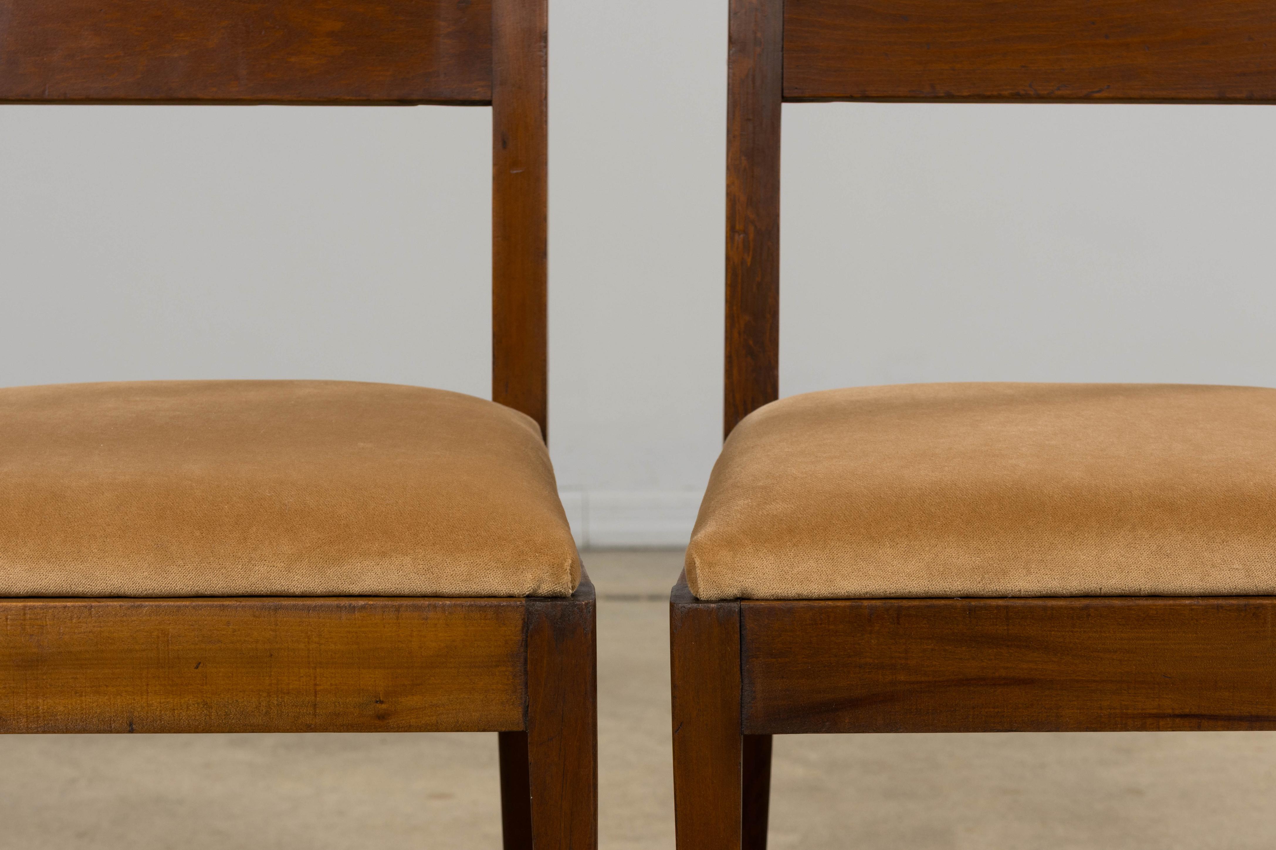 Una raffinata coppia di poltroncine francesi Art Déco, provenienti dalla Provenza, in Francia. Realizzata in mogano, ogni sedia presenta uno schienale rettangolare con una leggera curva e proporzioni pulite e lineari che si assottigliano in gambe